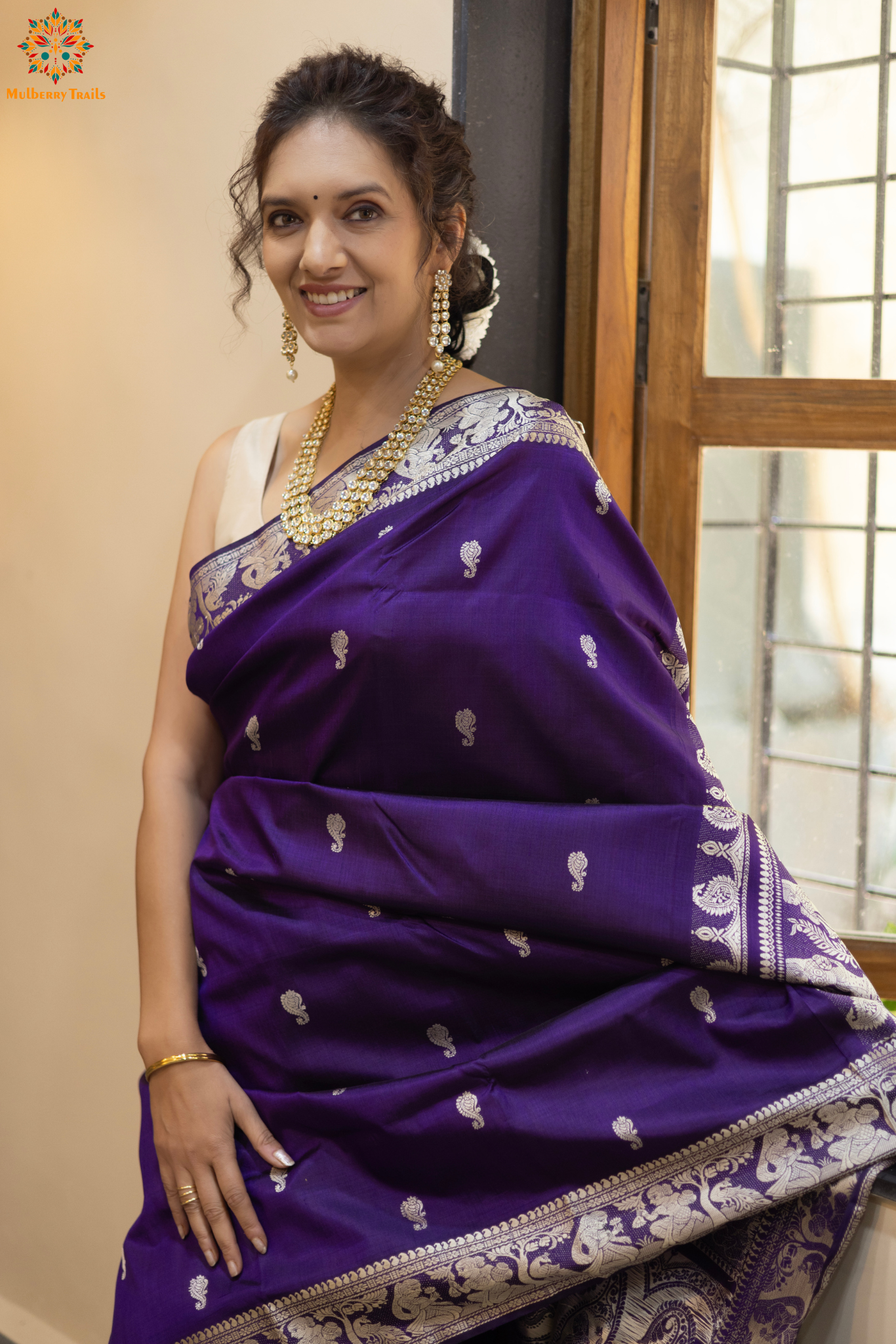 Woman wearing a traditional baluchari saree in a room with a desk and lamp. Woman in a carrot red and silver resham work saree standing indoors with a desk and lamp in the background.
Baluchari – Pure Silk Baluchari Saree
1. “Pure silk Baluchari saree with temple motif weave and Silver resham detailing for a regal look.”
2. “Silk Mark pure silk saree featuring intricate gold resham work motifs and rich texture.