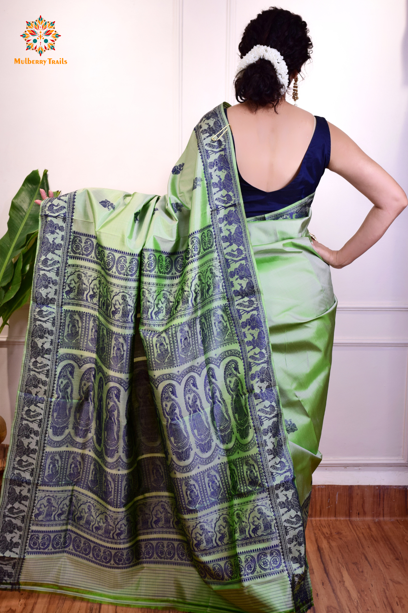 A woman wearing a Sage Green Baluchari Pure SIlk saree. purple baluchari silk , bengal silk saree with deer motif on pallu and ramayan, mahabharat motifs on pallu. This is a soft pure silk saree suitable for weddings, parties, festivities. suitable for Durga Puja shopping enthusiasts and diwali festival.