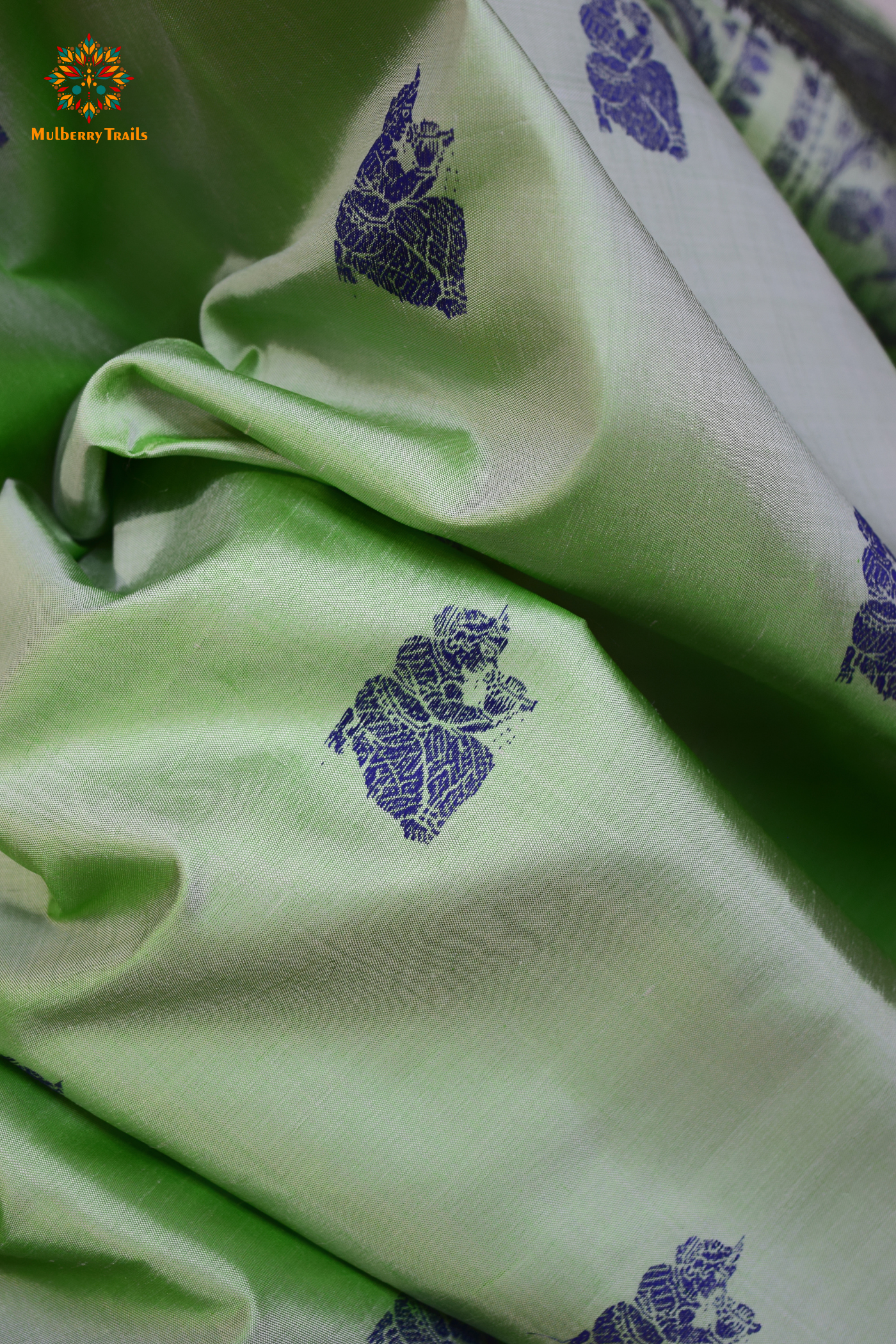 A woman wearing a Sage Green Baluchari Pure SIlk saree. purple baluchari silk , bengal silk saree with deer motif on pallu and ramayan, mahabharat motifs on pallu. This is a soft pure silk saree suitable for weddings, parties, festivities. suitable for Durga Puja shopping enthusiasts and diwali festival.