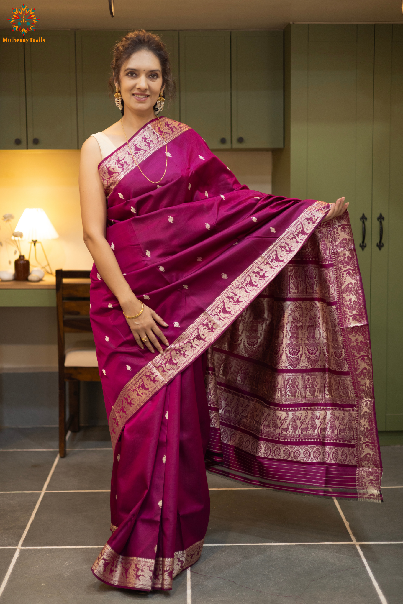 Woman wearing a traditional baluchari saree in a room with a desk and lamp. Woman in a carrot red and silver resham work saree standing indoors with a desk and lamp in the background.
Baluchari – Pure Silk Baluchari Saree
1. “Pure silk Baluchari saree with temple motif weave and Silver resham detailing for a regal look.”
2. “Silk Mark pure silk saree featuring intricate gold resham work motifs and rich texture.