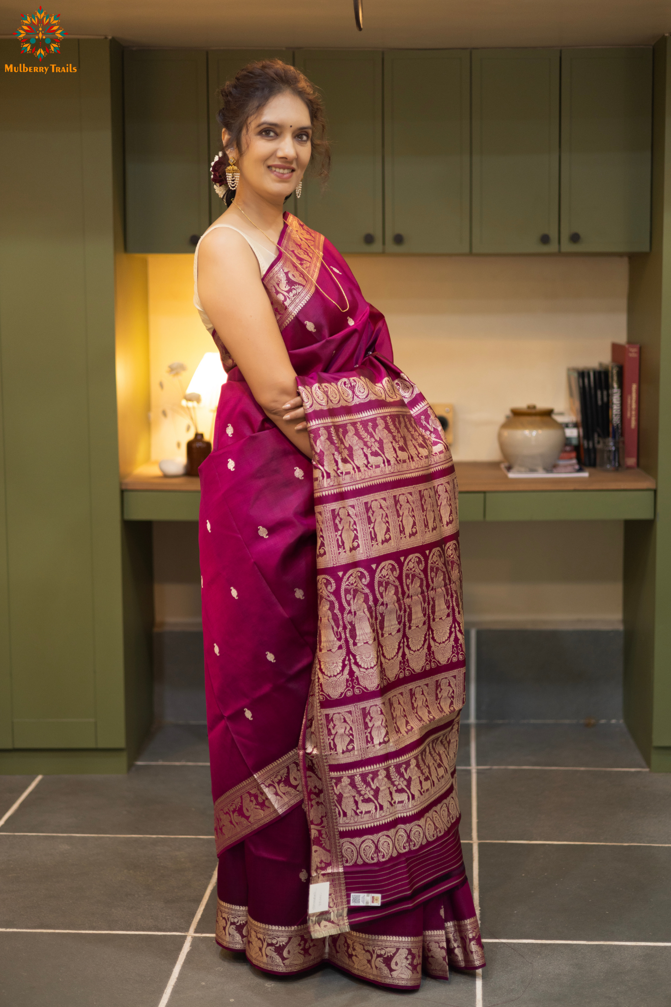Woman wearing a traditional baluchari saree in a room with a desk and lamp. Woman in a carrot red and silver resham work saree standing indoors with a desk and lamp in the background.
Baluchari – Pure Silk Baluchari Saree
1. “Pure silk Baluchari saree with temple motif weave and Silver resham detailing for a regal look.”
2. “Silk Mark pure silk saree featuring intricate gold resham work motifs and rich texture.