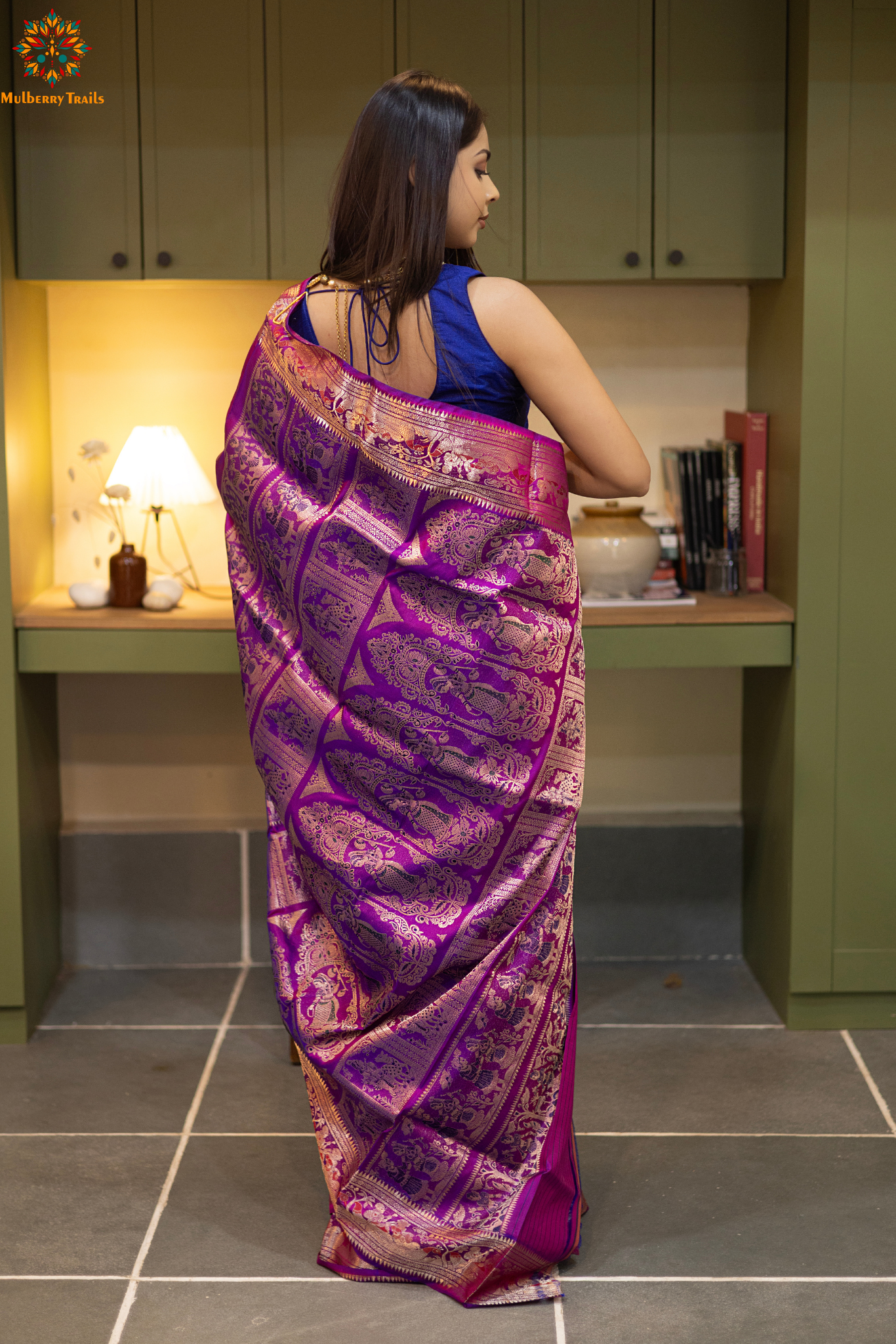 Woman wearing a purple saree with a pattern in a room. Woman in a pink saree standing in a elegant setting.
Swarnachari – Pure Silk Hazarbutta Saree
1. “Pure silk Swarnachari saree with hazarbutta thousand-motif weave and copper zari detailing for a regal look.”
2. “Silk Mark pure silk hazarbutta saree featuring intricate copper zari motifs and rich texture.”
Woman wearing a black and copper zari saree in a room with a desk and lamp.