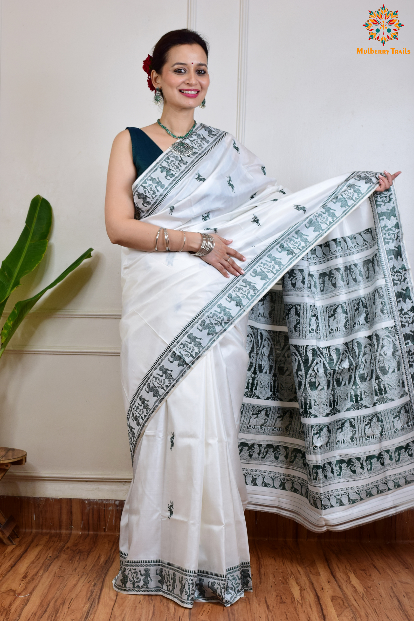 A woman wearing a White Baluchari Pure SIlk saree. White baluchari silk , bengal silk saree with deer motif on pallu and ramayan, mahabharat motifs on pallu. This is a soft pure silk saree suitable for weddings, parties, festivities. suitable for Durga Puja shopping enthusiasts and diwali festival.