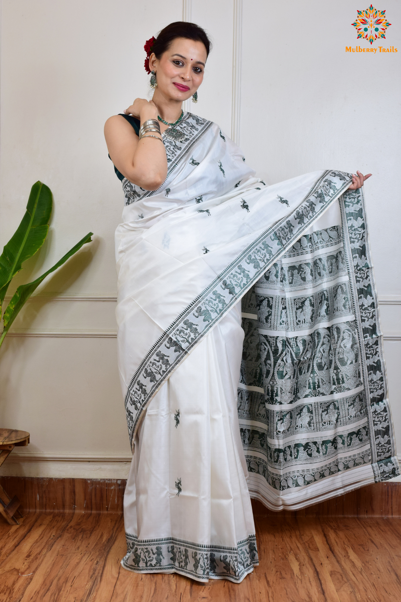 A woman wearing a White Baluchari Pure SIlk saree. White baluchari silk , bengal silk saree with deer motif on pallu and ramayan, mahabharat motifs on pallu. This is a soft pure silk saree suitable for weddings, parties, festivities. suitable for Durga Puja shopping enthusiasts and diwali festival.