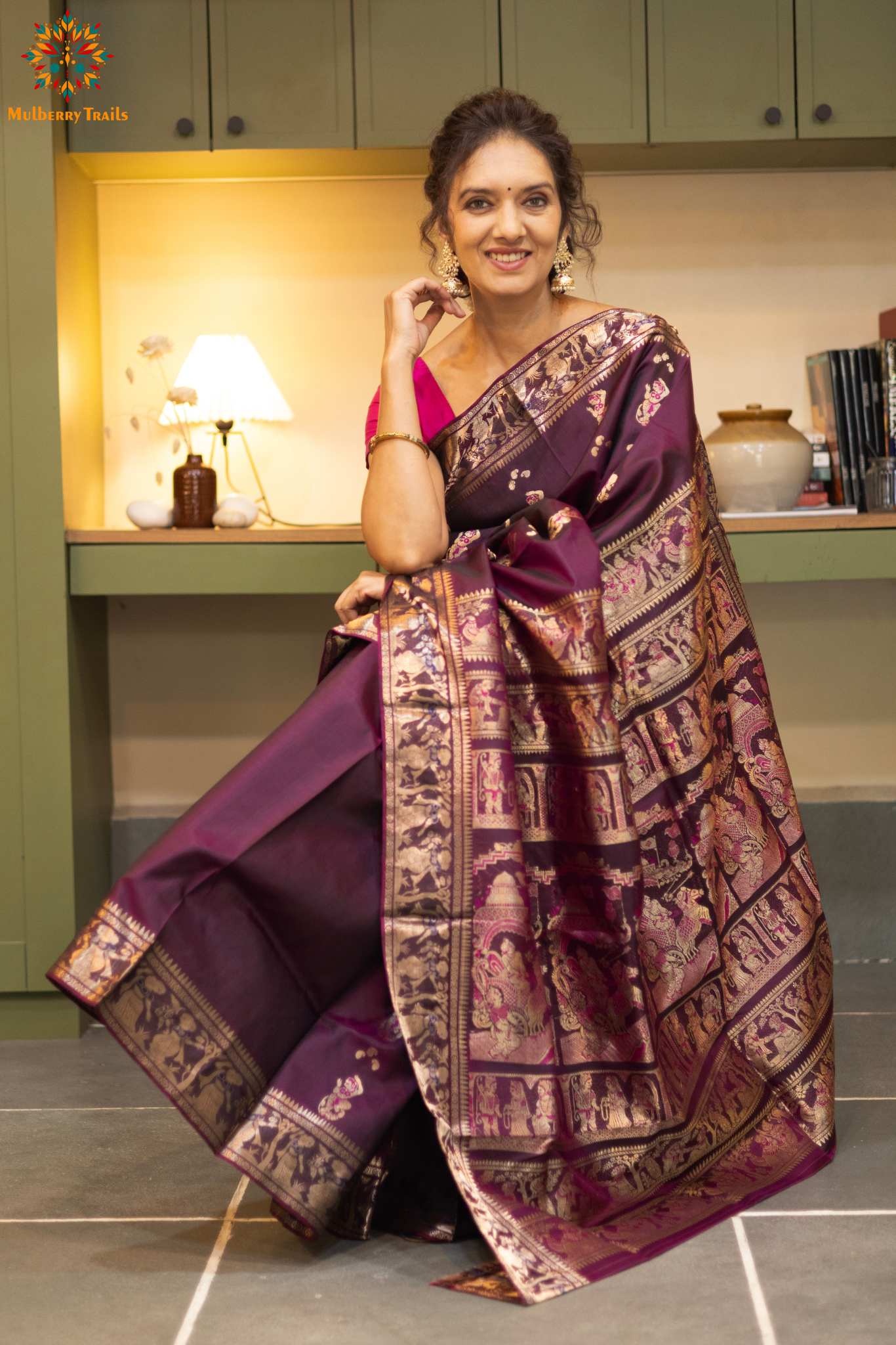 Woman wearing a purple saree with a pattern in a room. Woman in a wine saree standing in a elegant setting.
Swarnachari – Pure Silk Meenakari Saree
1. “Pure silk Swarnachari saree with meenakari motif weave and gold copper zari detailing for a regal look.”
2. “Silk Mark pure silk meenakari saree featuring intricate copper gold zari motifs and rich texture.”
Woman wearing a wine color swarnachari saree in a room with a desk and lamp.