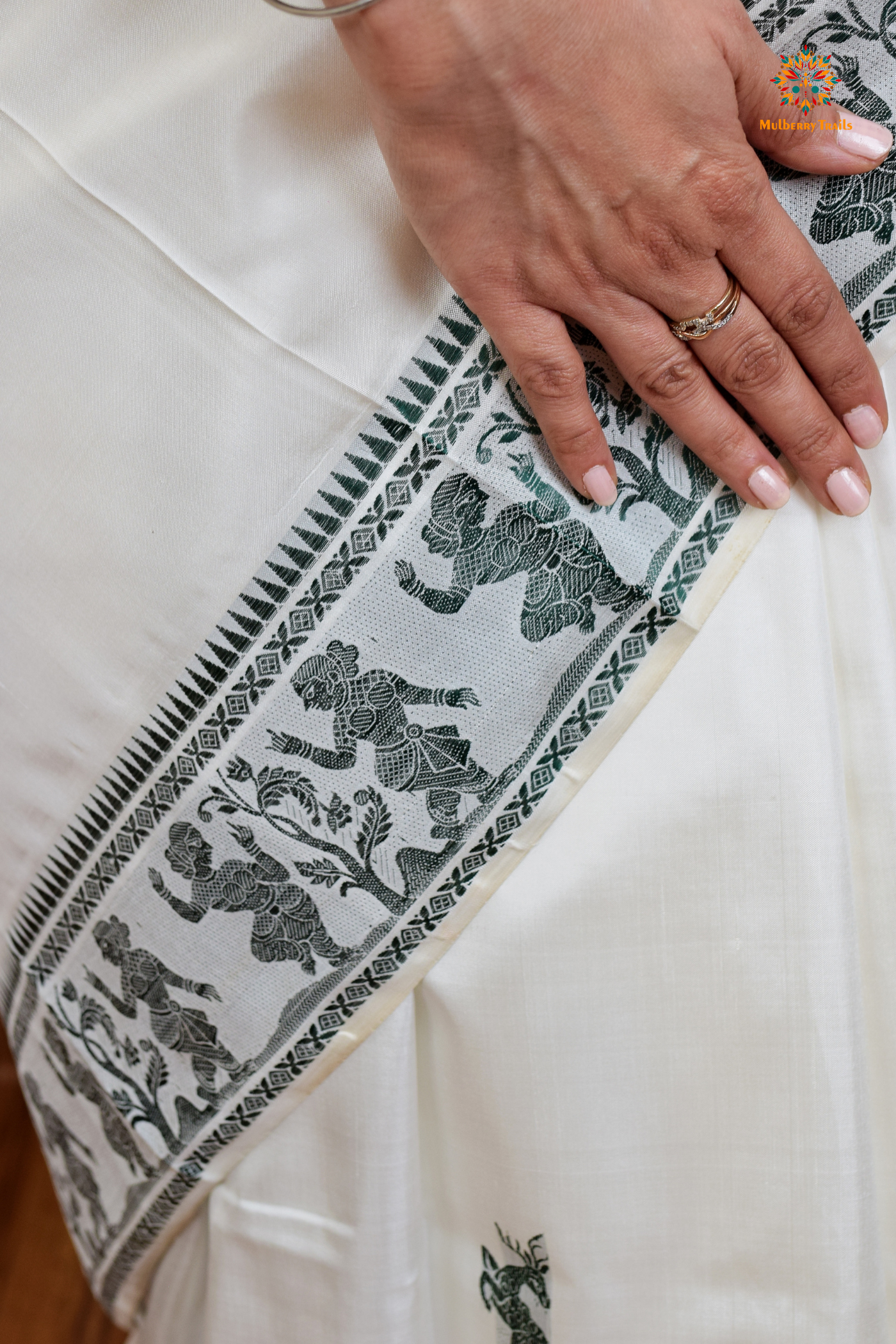 A woman wearing a White Baluchari Pure SIlk saree. White baluchari silk , bengal silk saree with deer motif on pallu and ramayan, mahabharat motifs on pallu. This is a soft pure silk saree suitable for weddings, parties, festivities. suitable for Durga Puja shopping enthusiasts and diwali festival.
