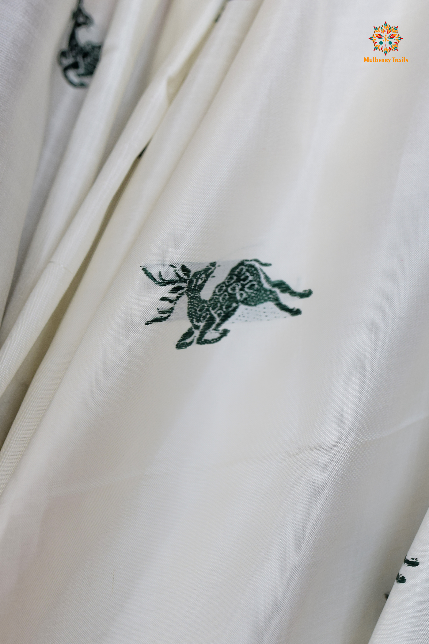 A woman wearing a White Baluchari Pure SIlk saree. White baluchari silk , bengal silk saree with deer motif on pallu and ramayan, mahabharat motifs on pallu. This is a soft pure silk saree suitable for weddings, parties, festivities. suitable for Durga Puja shopping enthusiasts and diwali festival.