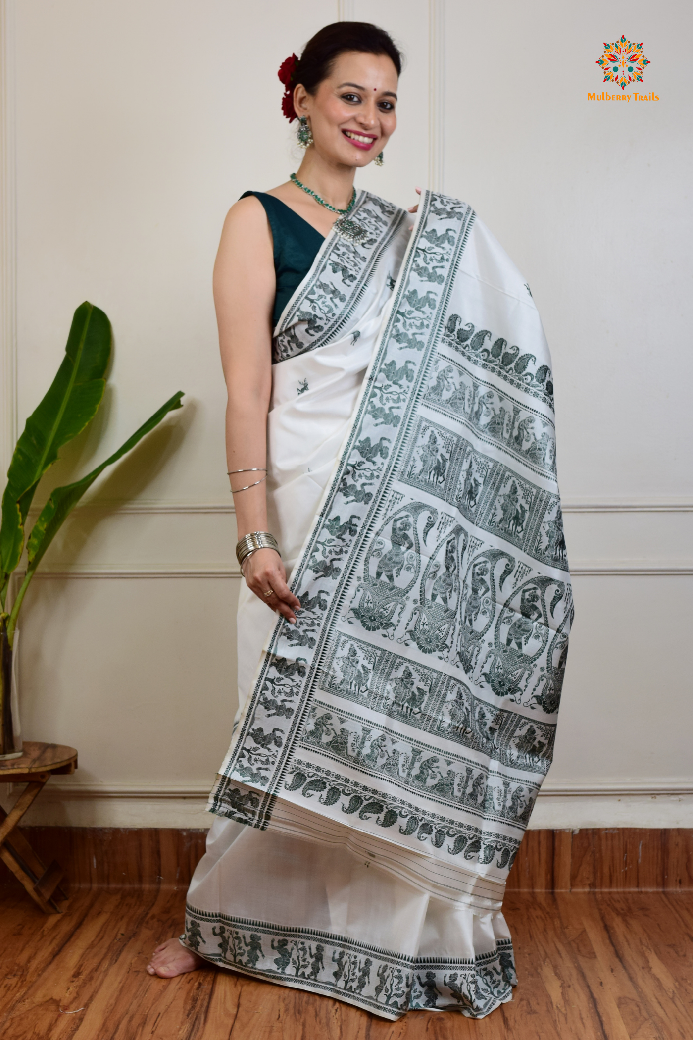A woman wearing a White Baluchari Pure SIlk saree. White baluchari silk , bengal silk saree with deer motif on pallu and ramayan, mahabharat motifs on pallu. This is a soft pure silk saree suitable for weddings, parties, festivities. suitable for Durga Puja shopping enthusiasts and diwali festival.