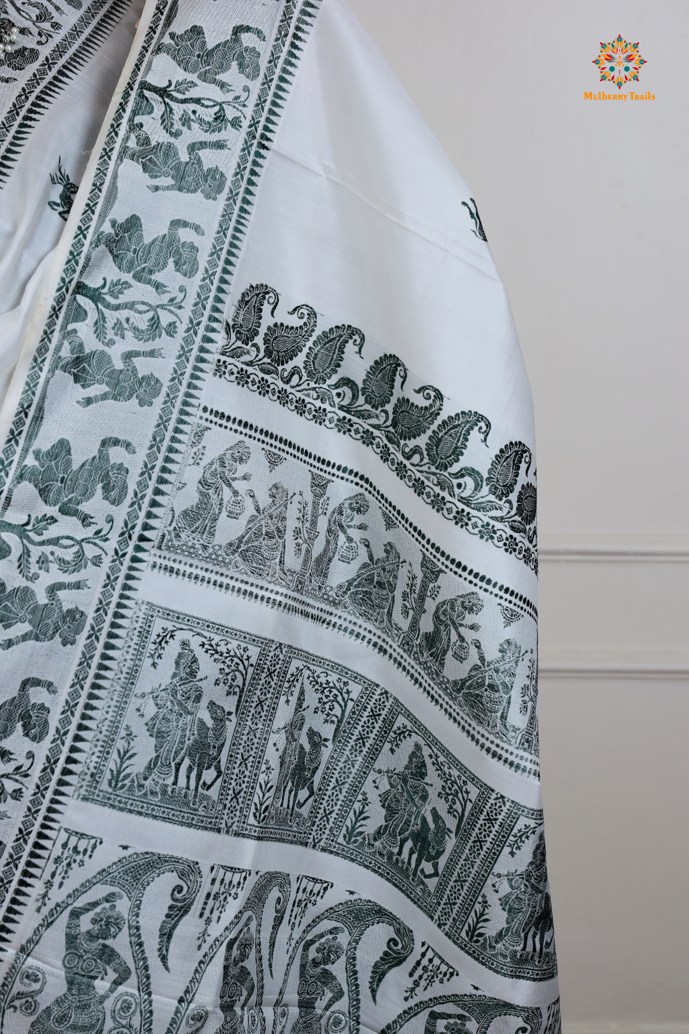 A woman wearing a White Baluchari Pure SIlk saree. White baluchari silk , bengal silk saree with deer motif on pallu and ramayan, mahabharat motifs on pallu. This is a soft pure silk saree suitable for weddings, parties, festivities. suitable for Durga Puja shopping enthusiasts and diwali festival.