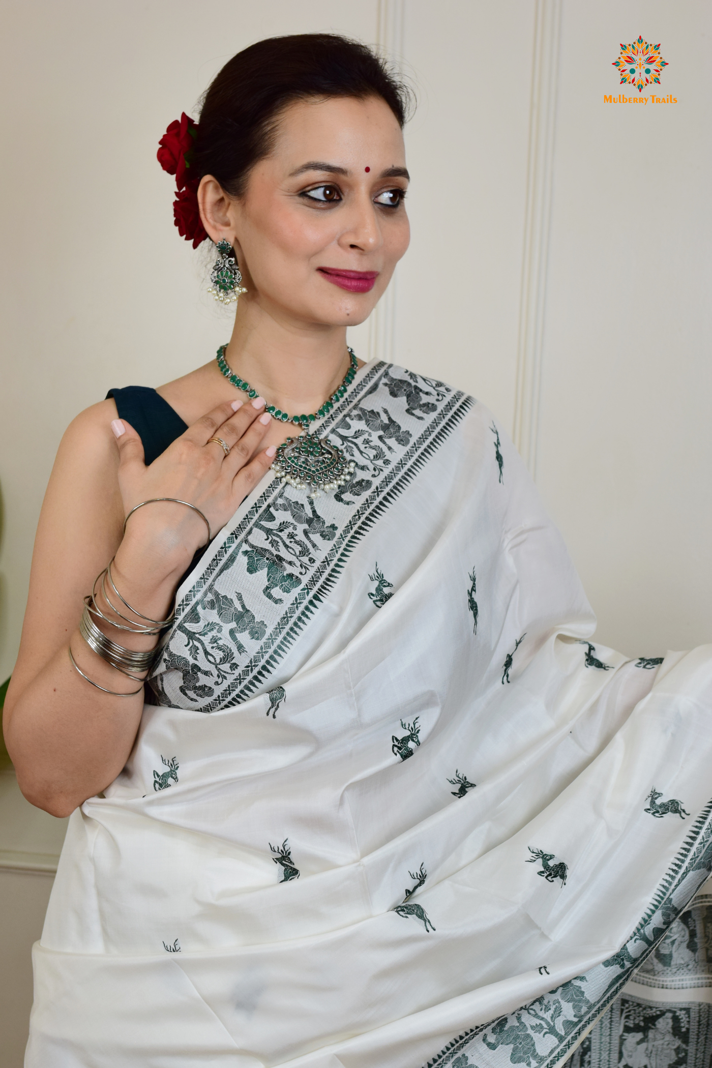 A woman wearing a White Baluchari Pure SIlk saree. White baluchari silk , bengal silk saree with deer motif on pallu and ramayan, mahabharat motifs on pallu. This is a soft pure silk saree suitable for weddings, parties, festivities. suitable for Durga Puja shopping enthusiasts and diwali festival.