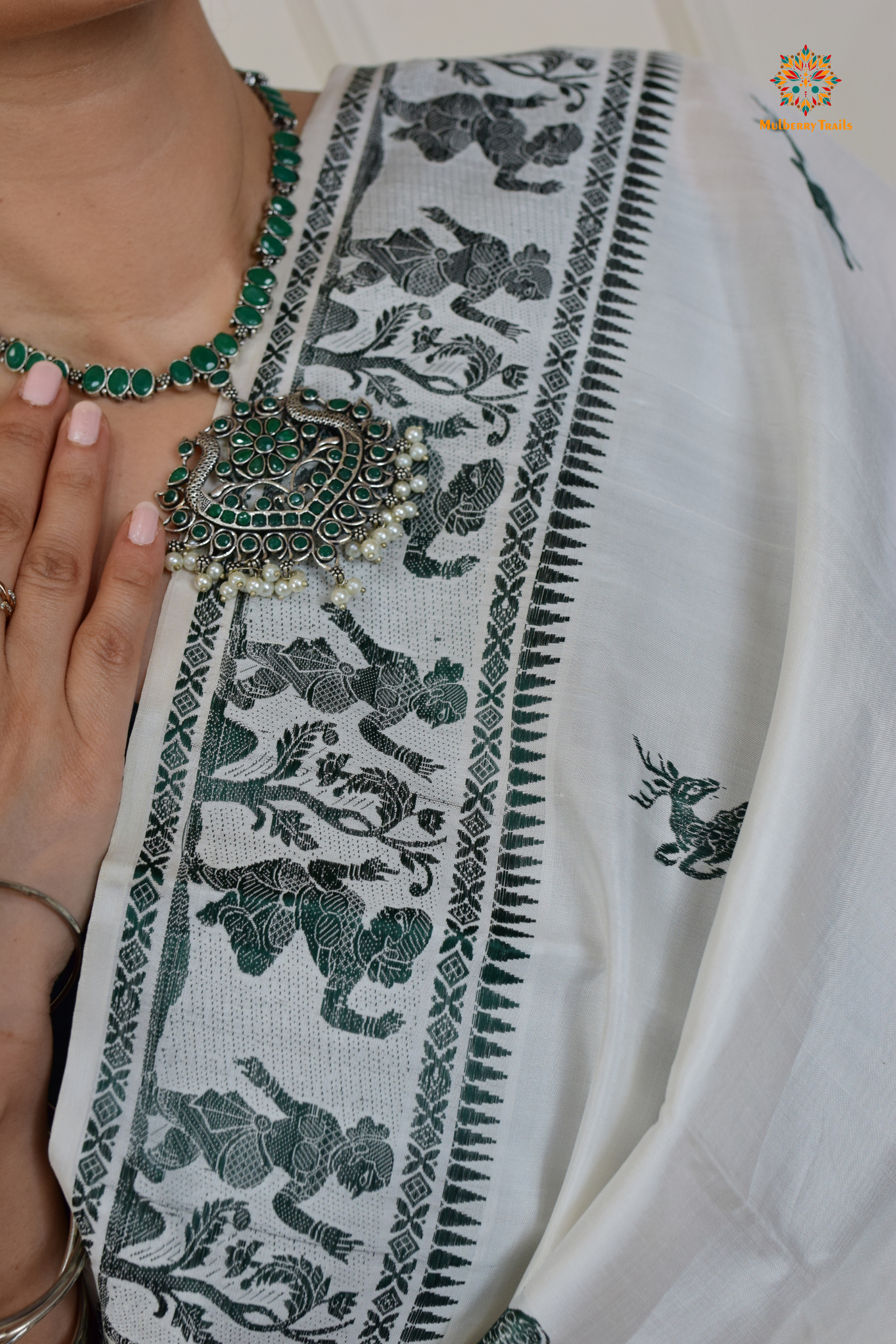 A woman wearing a White Baluchari Pure SIlk saree. White baluchari silk , bengal silk saree with deer motif on pallu and ramayan, mahabharat motifs on pallu. This is a soft pure silk saree suitable for weddings, parties, festivities. suitable for Durga Puja shopping enthusiasts and diwali festival.