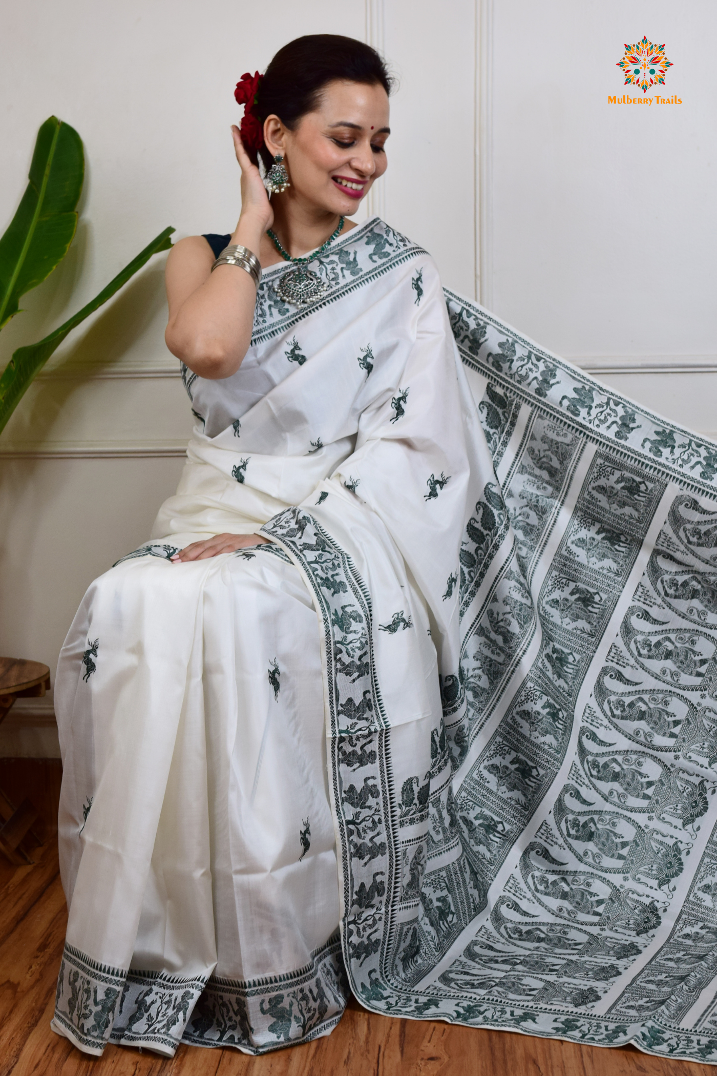 A woman wearing a White Baluchari Pure SIlk saree. White baluchari silk , bengal silk saree with deer motif on pallu and ramayan, mahabharat motifs on pallu. This is a soft pure silk saree suitable for weddings, parties, festivities. suitable for Durga Puja shopping enthusiasts and diwali festival.
