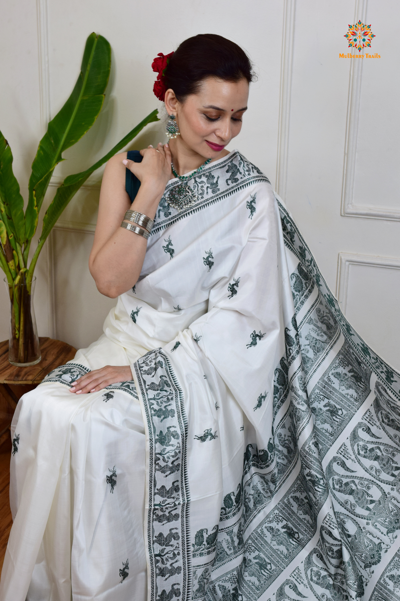 A woman wearing a White Baluchari Pure SIlk saree. White baluchari silk , bengal silk saree with deer motif on pallu and ramayan, mahabharat motifs on pallu. This is a soft pure silk saree suitable for weddings, parties, festivities. suitable for Durga Puja shopping enthusiasts and diwali festival.
