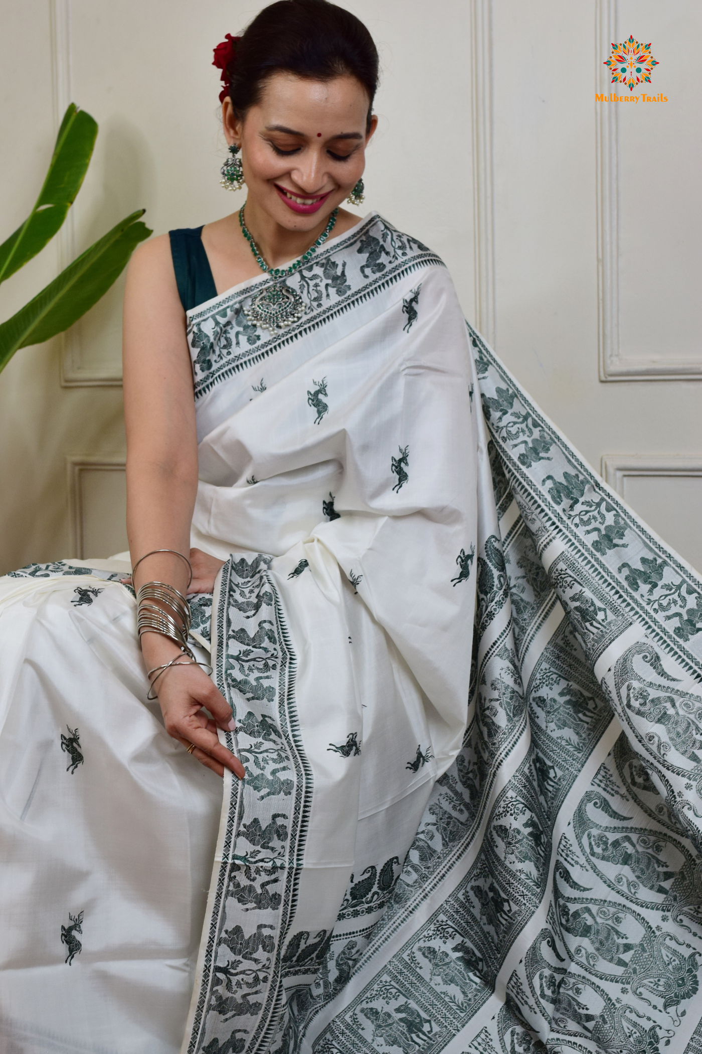 A woman wearing a White Baluchari Pure SIlk saree. White baluchari silk , bengal silk saree with deer motif on pallu and ramayan, mahabharat motifs on pallu. This is a soft pure silk saree suitable for weddings, parties, festivities. suitable for Durga Puja shopping enthusiasts and diwali festival.