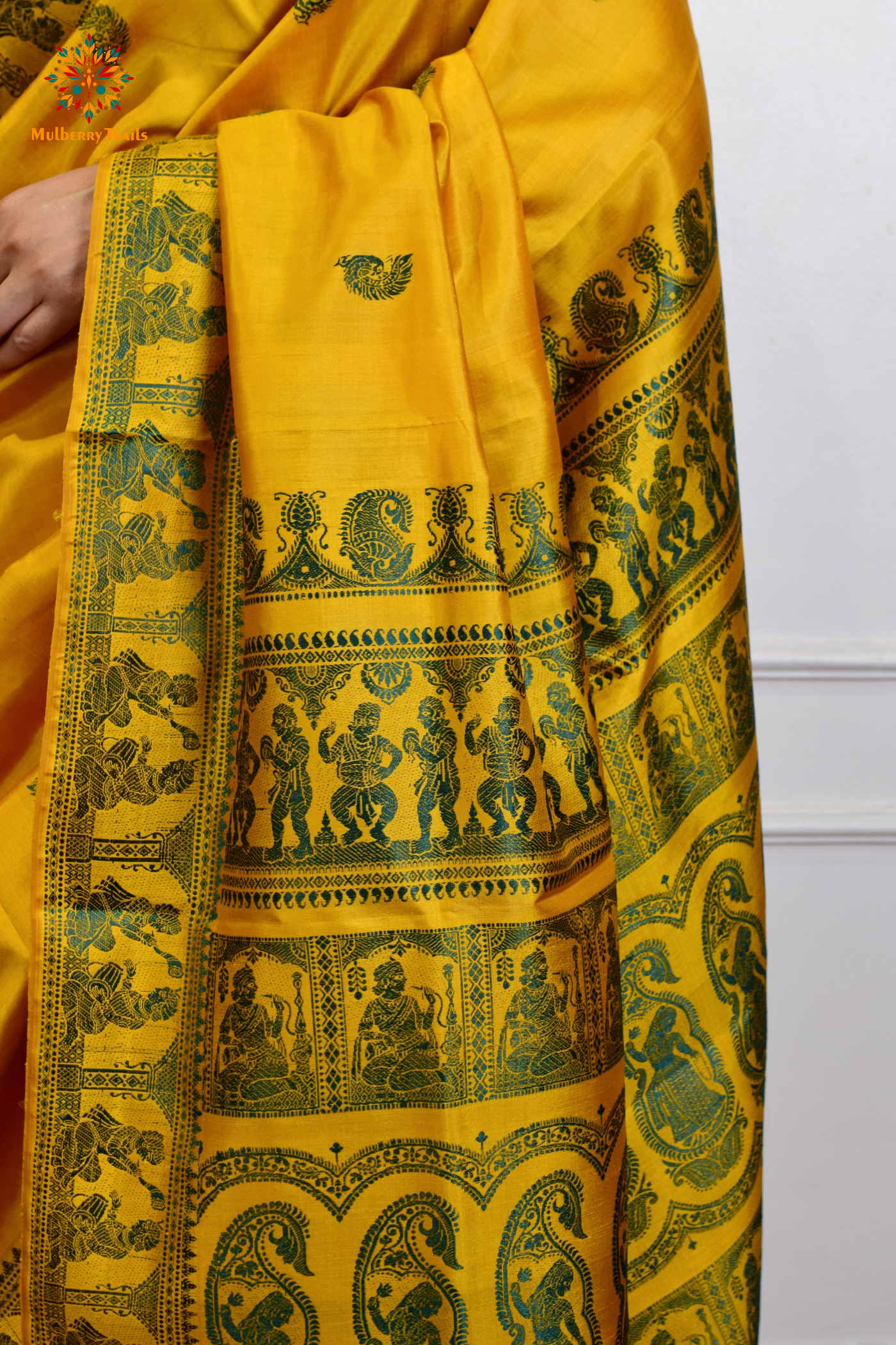 A woman wearing a Yellow Baluchari Pure SIlk saree. purple baluchari silk , bengal silk saree with deer motif on pallu and ramayan, mahabharat motifs on pallu. This is a soft pure silk saree suitable for weddings, parties, festivities. suitable for Durga Puja shopping enthusiasts and diwali festival. 
