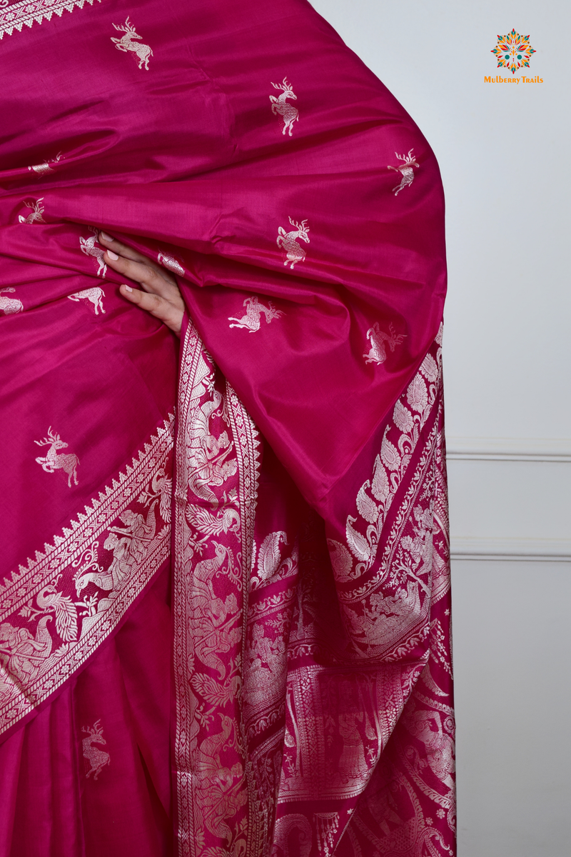 A woman wearing a Pink Baluchari Pure SIlk saree. Pink baluchari silk , bengal silk saree with deer motif on pallu and ramayan, mahabharat motifs on pallu. This is a soft pure silk saree suitable for weddings, parties, festivities. suitable for Durga Puja shopping enthusiasts and diwali festival. 