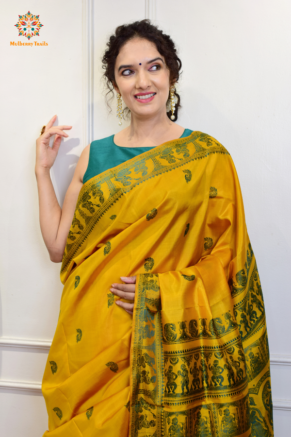 A woman wearing a Yellow Baluchari Pure SIlk saree. purple baluchari silk , bengal silk saree with deer motif on pallu and ramayan, mahabharat motifs on pallu. This is a soft pure silk saree suitable for weddings, parties, festivities. suitable for Durga Puja shopping enthusiasts and diwali festival. 