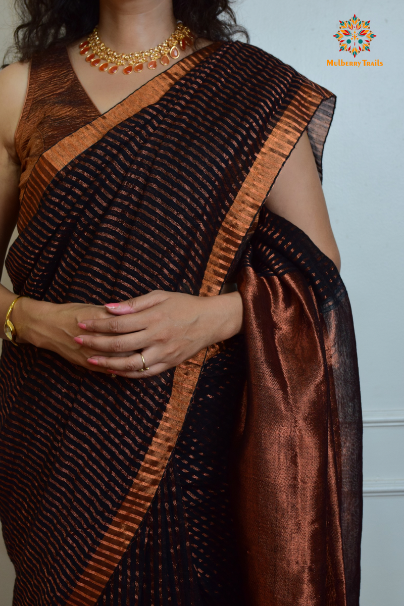 Woman celebrating Indian Festivals draped in Premium Handwoven Linen Saree / Sari. Comfortable and contemporary design of sari is perfect for attending weddings or festivals. Premium saree for festivals, sophisticated saree, Luxury contemporary sari linen saree, handloom, stripes, tissue, unique copper zari work border, Model wearing Linen sari, Saree and blouse combination, saree for friends wedding, saree for wedding gift, saree for festive wear, sari for ganpati occassion, saree for diwali