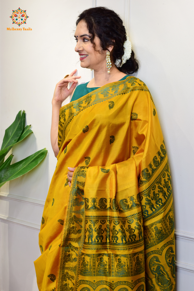 A woman wearing a Yellow Baluchari Pure SIlk saree. purple baluchari silk , bengal silk saree with deer motif on pallu and ramayan, mahabharat motifs on pallu. This is a soft pure silk saree suitable for weddings, parties, festivities. suitable for Durga Puja shopping enthusiasts and diwali festival. 