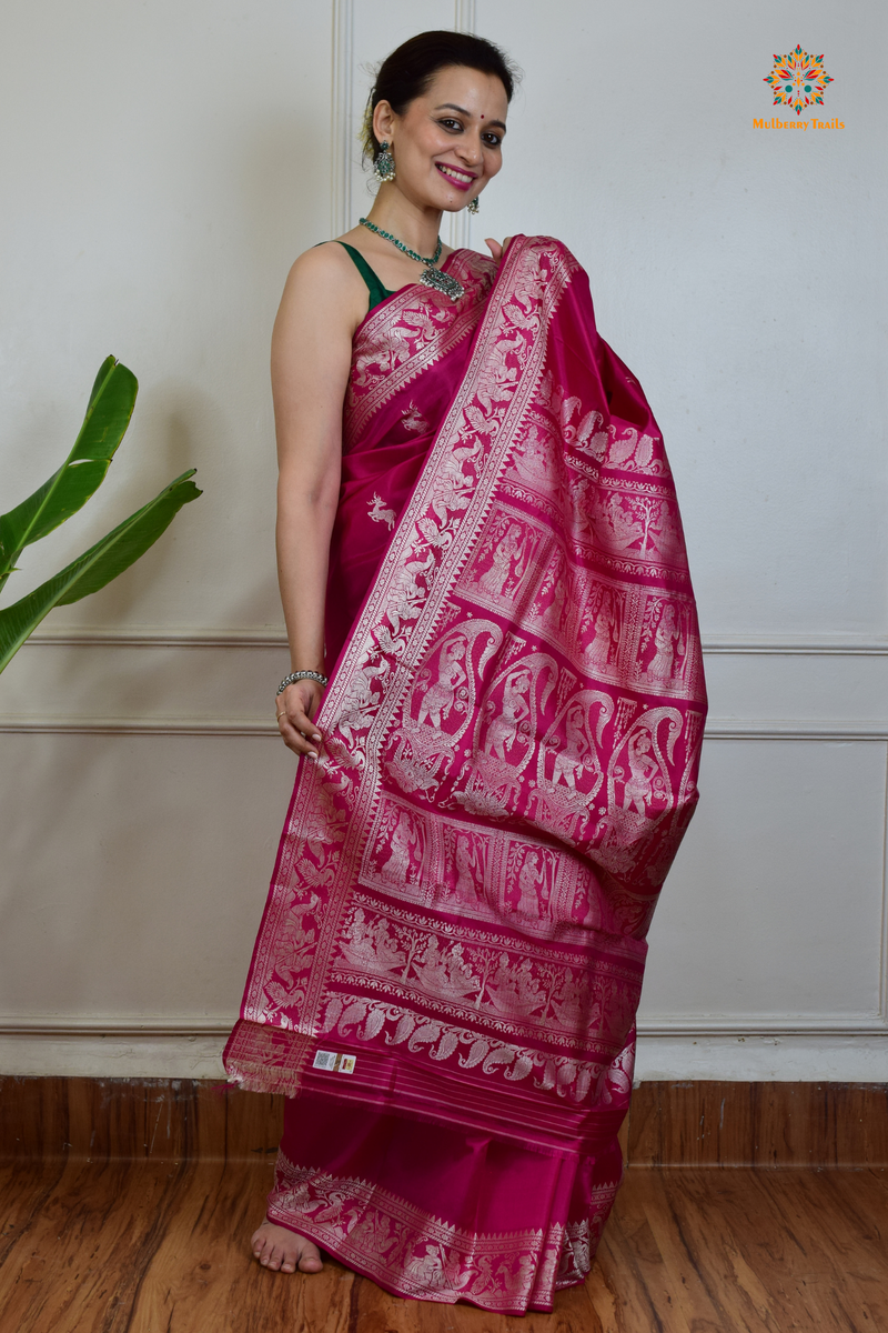 A woman wearing a Pink Baluchari Pure SIlk saree. Pink baluchari silk , bengal silk saree with deer motif on pallu and ramayan, mahabharat motifs on pallu. This is a soft pure silk saree suitable for weddings, parties, festivities. suitable for Durga Puja shopping enthusiasts and diwali festival. 