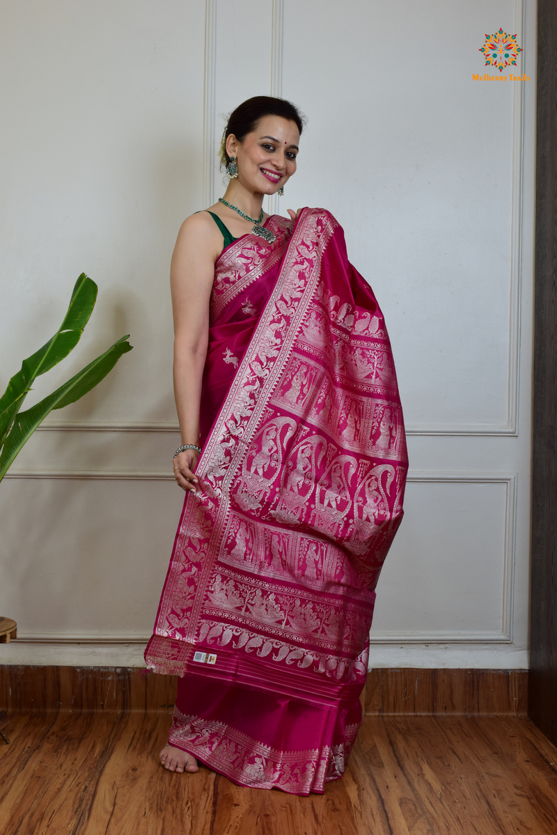 A woman wearing a Pink Baluchari Pure SIlk saree. Pink baluchari silk , bengal silk saree with deer motif on pallu and ramayan, mahabharat motifs on pallu. This is a soft pure silk saree suitable for weddings, parties, festivities. suitable for Durga Puja shopping enthusiasts and diwali festival. 