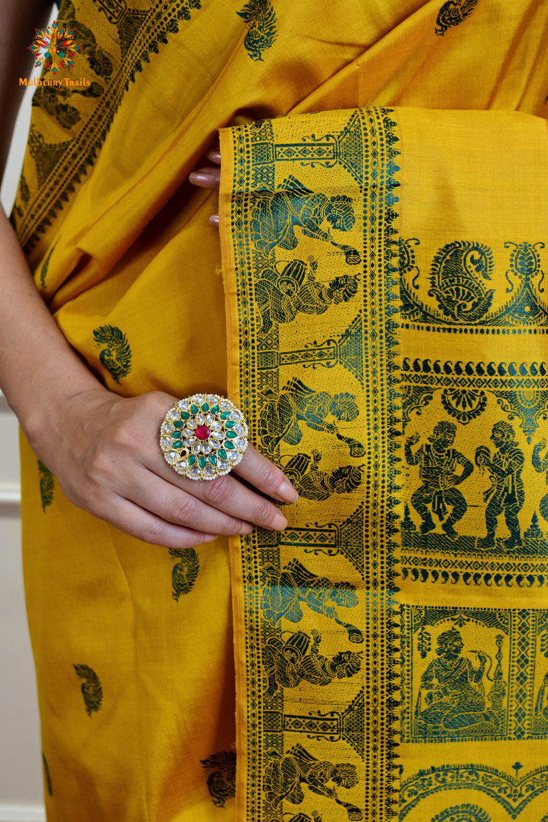 A woman wearing a Yellow Baluchari Pure SIlk saree. purple baluchari silk , bengal silk saree with deer motif on pallu and ramayan, mahabharat motifs on pallu. This is a soft pure silk saree suitable for weddings, parties, festivities. suitable for Durga Puja shopping enthusiasts and diwali festival. 