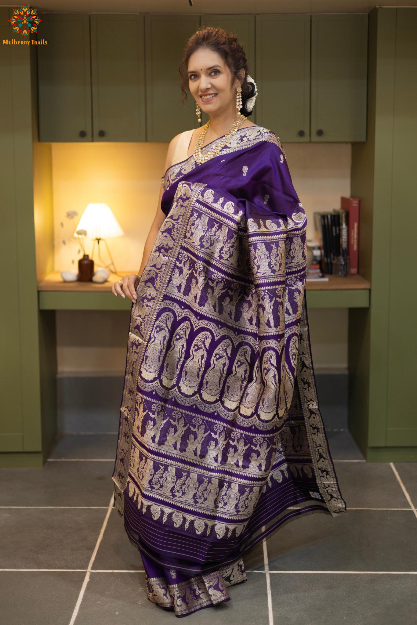 Woman wearing a traditional baluchari saree in a room with a desk and lamp. Woman in a carrot red and silver resham work saree standing indoors with a desk and lamp in the background.

Baluchari – Pure Silk Baluchari Saree

1. “Pure silk Baluchari saree with temple motif weave and Silver resham detailing for a regal look.”

2. “Silk Mark pure silk saree featuring intricate gold resham work motifs and rich texture. 