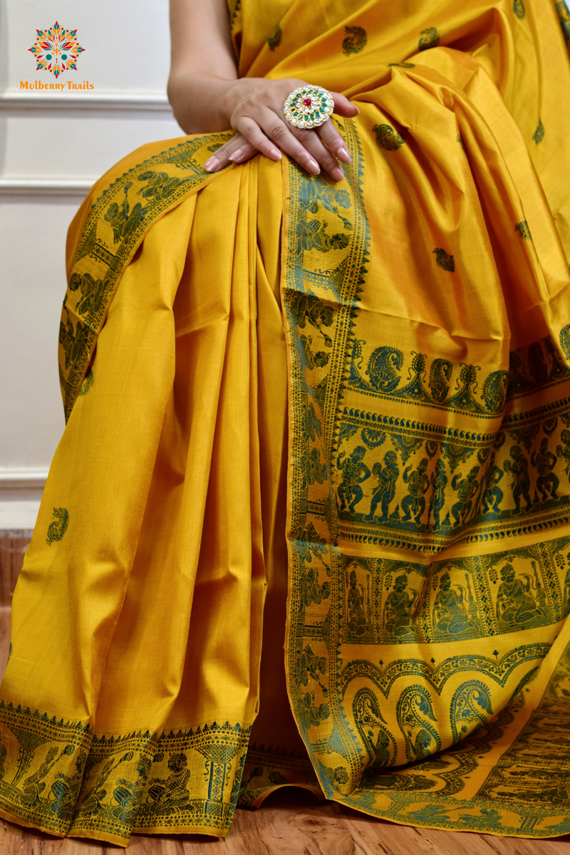 A woman wearing a Yellow Baluchari Pure SIlk saree. purple baluchari silk , bengal silk saree with deer motif on pallu and ramayan, mahabharat motifs on pallu. This is a soft pure silk saree suitable for weddings, parties, festivities. suitable for Durga Puja shopping enthusiasts and diwali festival. 