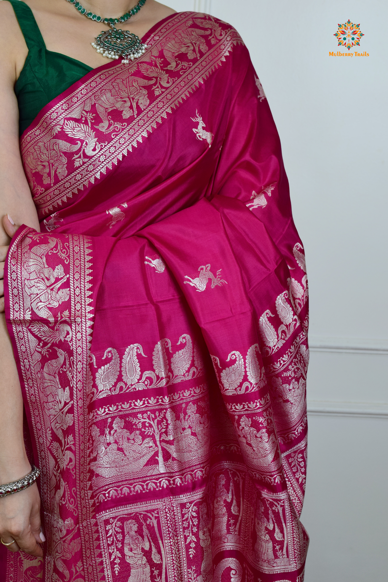 A woman wearing a Pink Baluchari Pure SIlk saree. Pink baluchari silk , bengal silk saree with deer motif on pallu and ramayan, mahabharat motifs on pallu. This is a soft pure silk saree suitable for weddings, parties, festivities. suitable for Durga Puja shopping enthusiasts and diwali festival. 