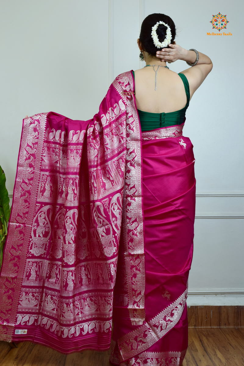 A woman wearing a Pink Baluchari Pure SIlk saree. Pink baluchari silk , bengal silk saree with deer motif on pallu and ramayan, mahabharat motifs on pallu. This is a soft pure silk saree suitable for weddings, parties, festivities. suitable for Durga Puja shopping enthusiasts and diwali festival. 