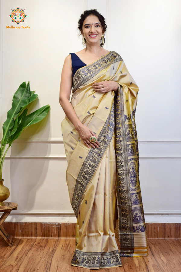 A woman wearing a Beige Baluchari Pure SIlk saree. purple baluchari silk , bengal silk saree with deer motif on pallu and ramayan, mahabharat motifs on pallu. This is a soft pure silk saree suitable for weddings, parties, festivities. suitable for Durga Puja shopping enthusiasts and diwali festival. 