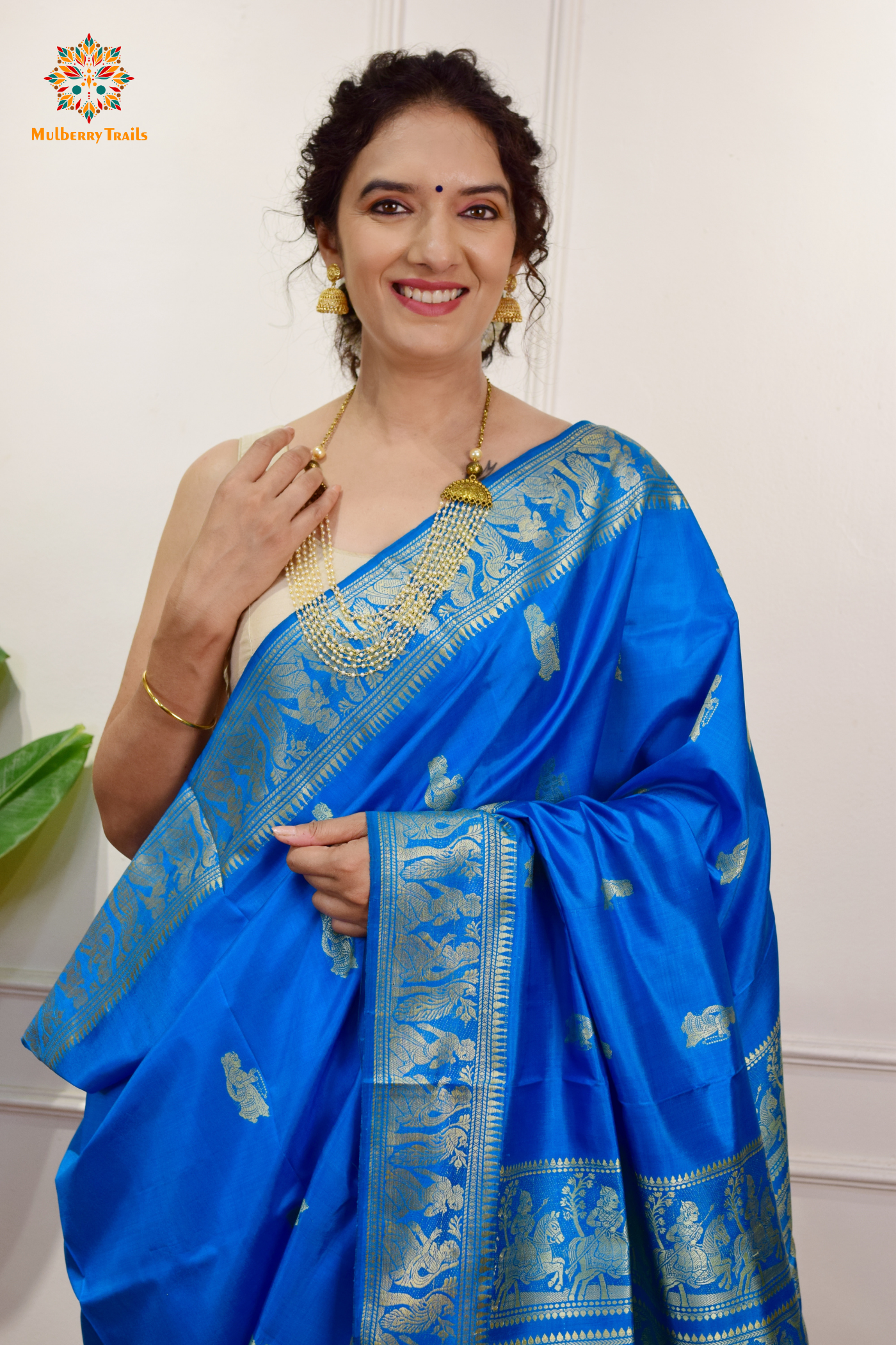 A woman wearing a Blue Baluchari Pure SIlk saree. Blue baluchari silk , bengal silk saree with deer motif on pallu and ramayan, mahabharat motifs on pallu. This is a soft pure silk saree suitable for weddings, parties, festivities. suitable for Durga Puja shopping enthusiasts and diwali festival. 