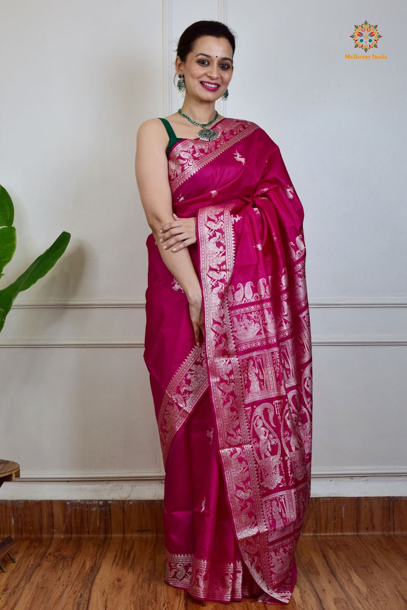 A woman wearing a Pink Baluchari Pure SIlk saree. Pink baluchari silk , bengal silk saree with deer motif on pallu and ramayan, mahabharat motifs on pallu. This is a soft pure silk saree suitable for weddings, parties, festivities. suitable for Durga Puja shopping enthusiasts and diwali festival. 