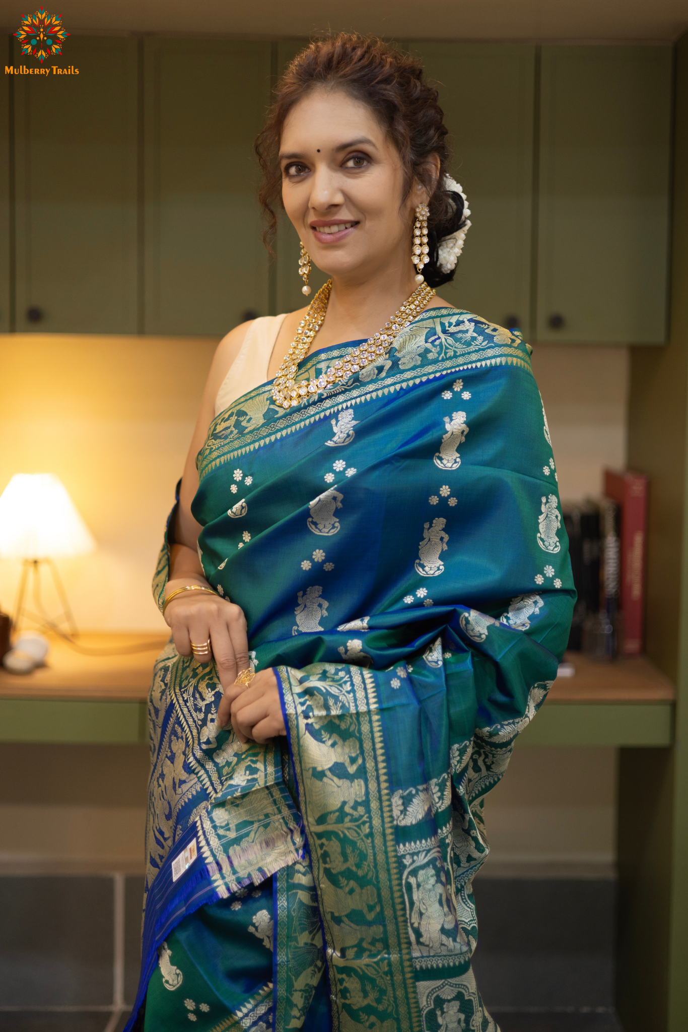 Woman wearing a traditional baluchari saree in a room with a desk and lamp. Woman in a Peacock blue and silver resham work saree standing indoors with a desk and lamp in the background.

Baluchari – Pure Silk Baluchari Saree

1. “Pure silk Baluchari saree with meenakari motif weave and Silver resham detailing for a regal look.”

2. “Silk Mark pure silk meenakari saree featuring intricate gold resham work motifs and rich texture. 