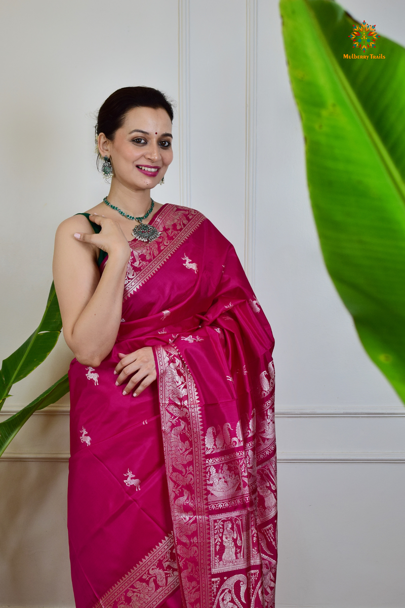 A woman wearing a Pink Baluchari Pure SIlk saree. Pink baluchari silk , bengal silk saree with deer motif on pallu and ramayan, mahabharat motifs on pallu. This is a soft pure silk saree suitable for weddings, parties, festivities. suitable for Durga Puja shopping enthusiasts and diwali festival. 