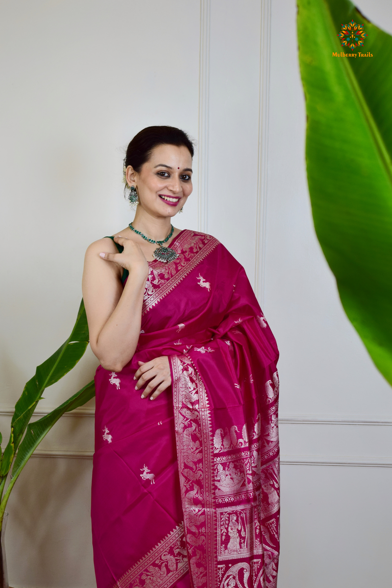 A woman wearing a Pink Baluchari Pure SIlk saree. Pink baluchari silk , bengal silk saree with deer motif on pallu and ramayan, mahabharat motifs on pallu. This is a soft pure silk saree suitable for weddings, parties, festivities. suitable for Durga Puja shopping enthusiasts and diwali festival. 