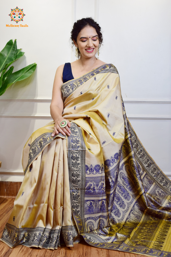 A woman wearing a Beige Baluchari Pure SIlk saree. purple baluchari silk , bengal silk saree with deer motif on pallu and ramayan, mahabharat motifs on pallu. This is a soft pure silk saree suitable for weddings, parties, festivities. suitable for Durga Puja shopping enthusiasts and diwali festival. 