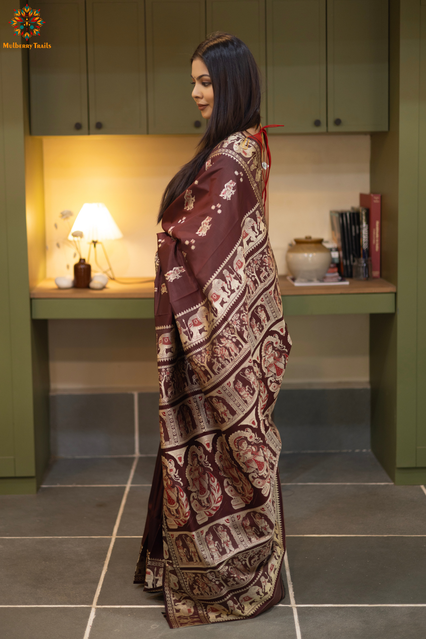 Woman in a Coffee brown and silver resham work saree standing indoors with a desk and lamp in the background.
Woman wearing a Coffee brown saree with a pattern in a elegant setting. 

Baluchari – Pure Silk Meenakari Saree

1. “Pure silk Baluchari Meenakari saree with meenakari motif weave and Silver resham detailing for a regal look.”

2. “Silk Mark pure silk meenakari saree featuring intricate gold resham work motifs and rich texture.” 