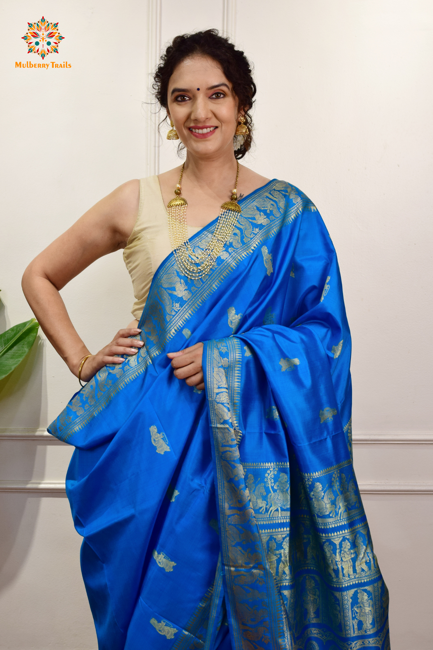 A woman wearing a Blue Baluchari Pure SIlk saree. Blue baluchari silk , bengal silk saree with deer motif on pallu and ramayan, mahabharat motifs on pallu. This is a soft pure silk saree suitable for weddings, parties, festivities. suitable for Durga Puja shopping enthusiasts and diwali festival. 