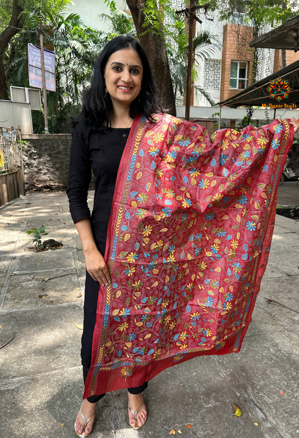 Elegant pure silk dupatta in peach Orange color, featuring intricate Kantha embroidery with vibrant floral and paisley motifs. The dupatta boasts a luxurious sheen and a rich texture, perfect for adding a touch of sophistication to any outfit. The hand-embroidered details highlight the traditional craftsmanship and artistry, making it a statement accessory for festive occasions or special events.