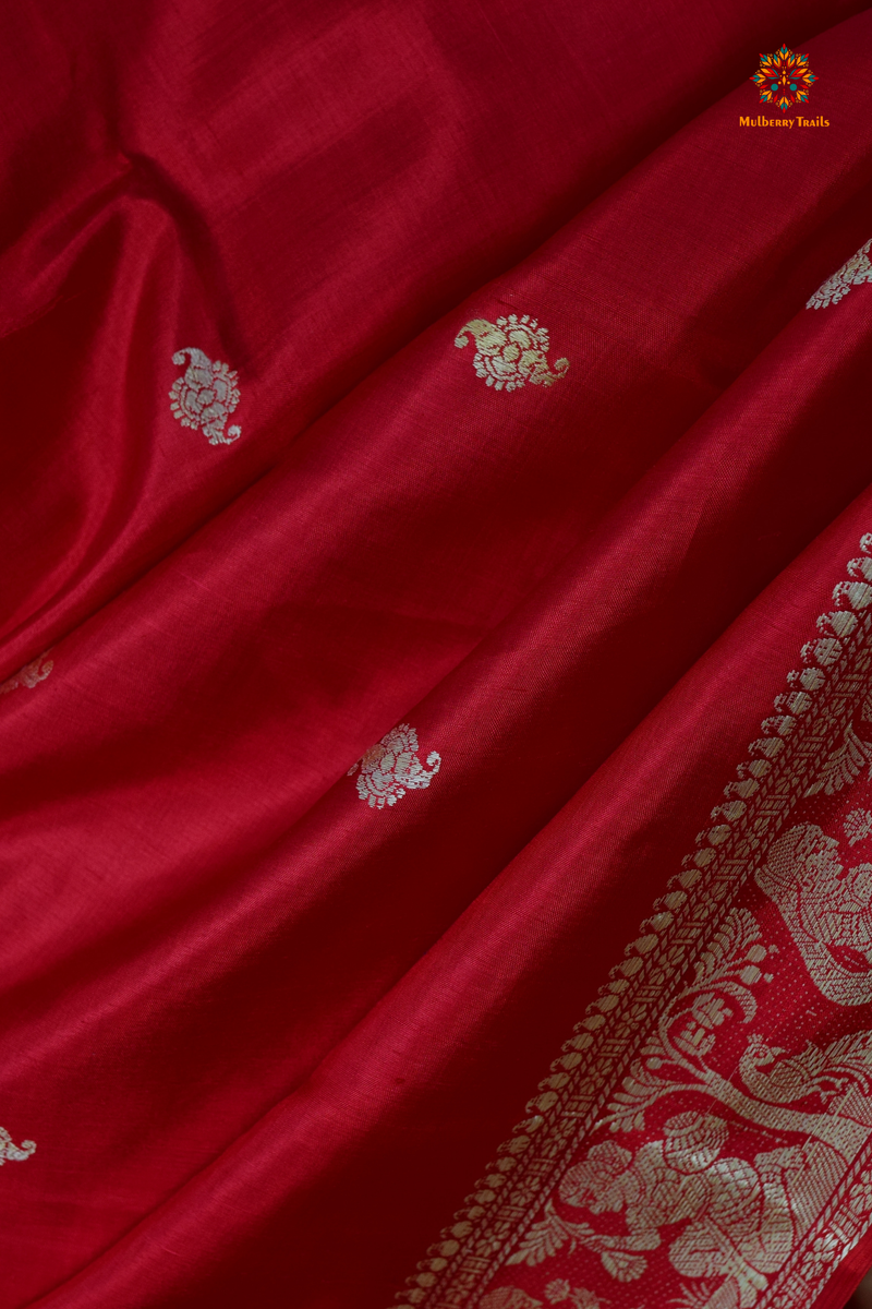 A woman wearing a Red Baluchari Pure SIlk saree. Red baluchari silk , bengal silk saree with deer motif on pallu and ramayan, mahabharat motifs on pallu. This is a soft pure silk saree suitable for weddings, parties, festivities. suitable for Durga Puja shopping enthusiasts and diwali festival. 