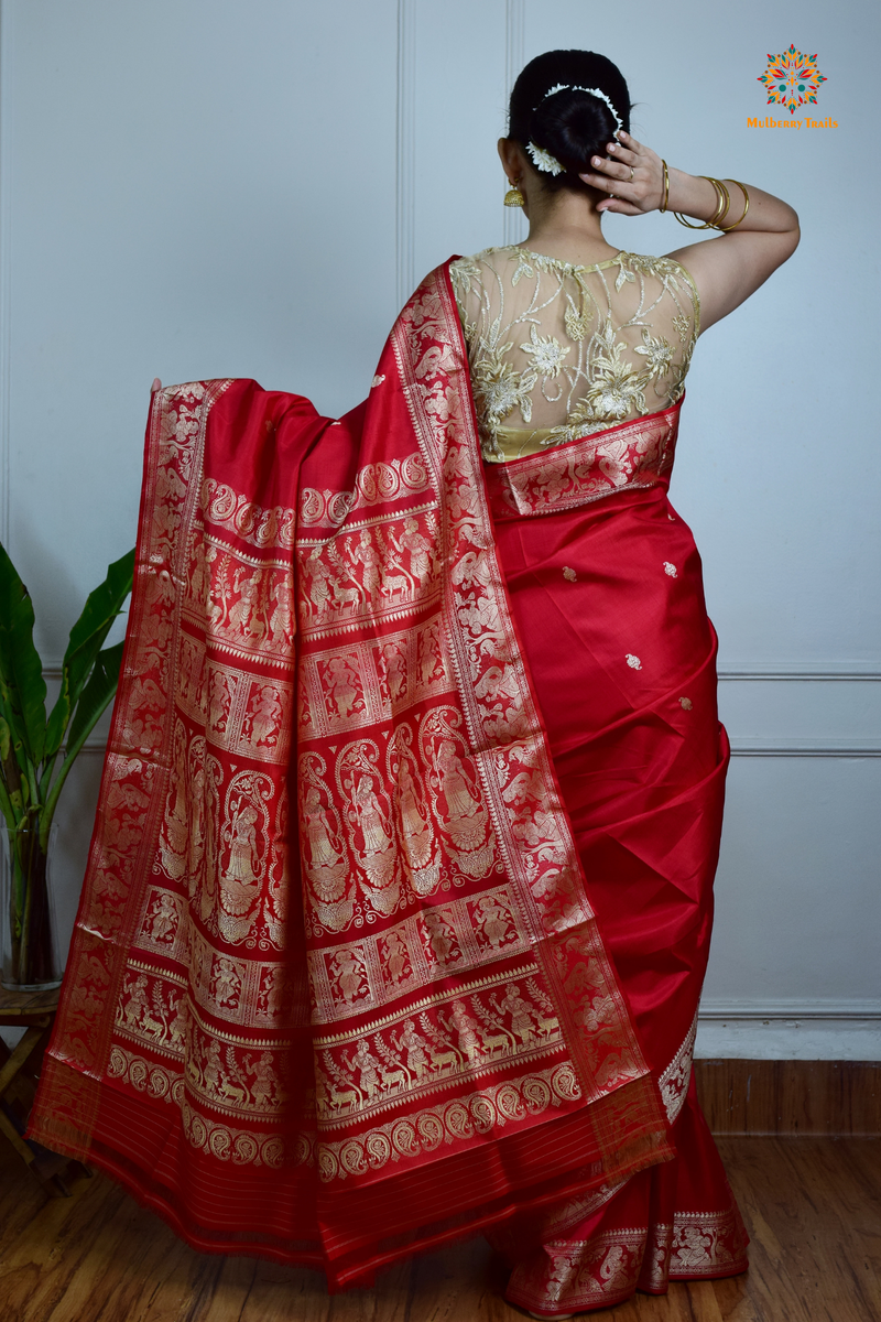 A woman wearing a Red Baluchari Pure SIlk saree. Red baluchari silk , bengal silk saree with deer motif on pallu and ramayan, mahabharat motifs on pallu. This is a soft pure silk saree suitable for weddings, parties, festivities. suitable for Durga Puja shopping enthusiasts and diwali festival. 