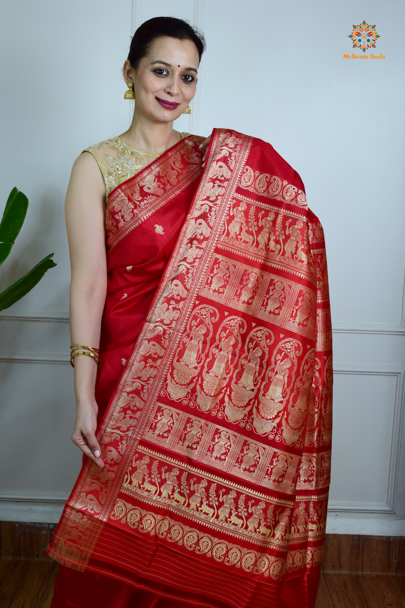 A woman wearing a Red Baluchari Pure SIlk saree. Red baluchari silk , bengal silk saree with deer motif on pallu and ramayan, mahabharat motifs on pallu. This is a soft pure silk saree suitable for weddings, parties, festivities. suitable for Durga Puja shopping enthusiasts and diwali festival. 