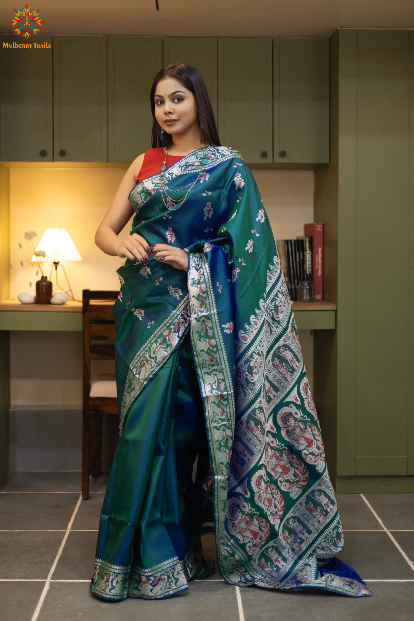 Woman in a Peacock blue and silver resham work saree standing indoors with a desk and lamp in the background.
Woman wearing a Peacock blue saree with a pattern in a elegant setting. 

Baluchari – Pure Silk Meenakari Saree

1. “Pure silk Baluchari Meenakari saree with meenakari motif weave and Silver resham detailing for a regal look.”

2. “Silk Mark pure silk meenakari saree featuring intricate gold resham work motifs and rich texture.” 