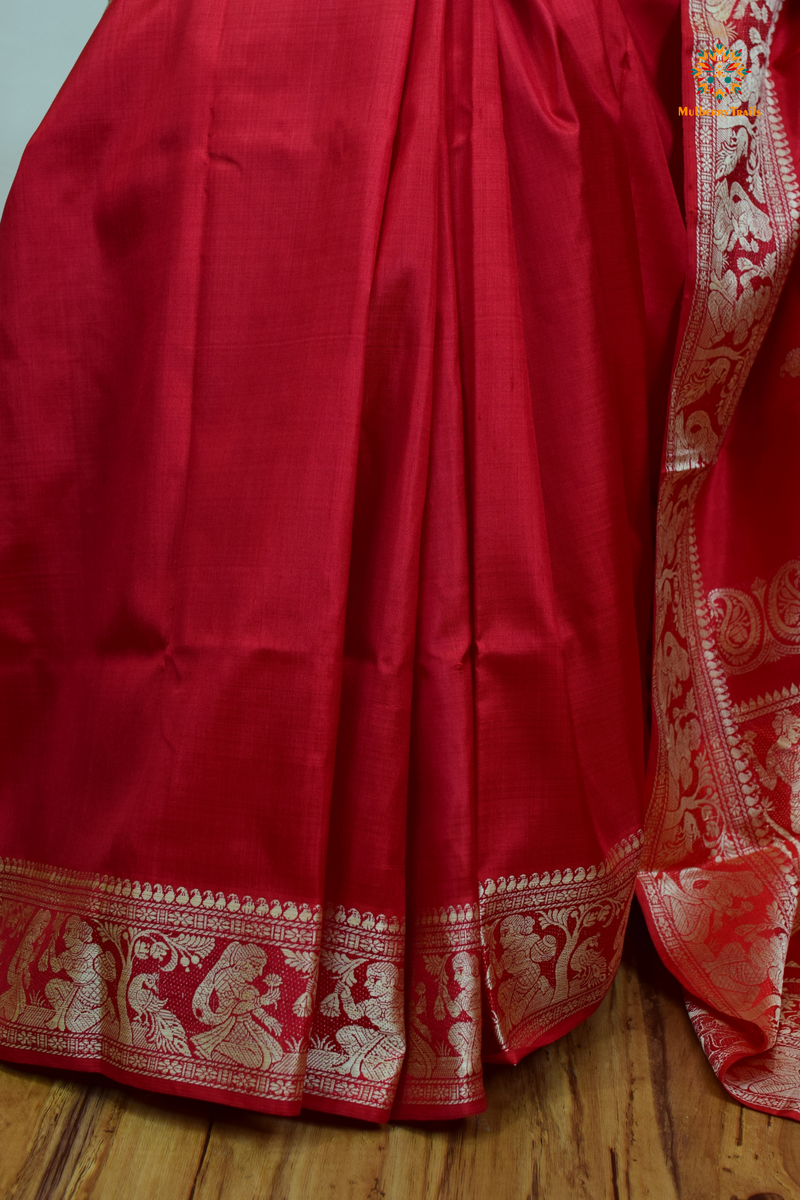 A woman wearing a Red Baluchari Pure SIlk saree. Red baluchari silk , bengal silk saree with deer motif on pallu and ramayan, mahabharat motifs on pallu. This is a soft pure silk saree suitable for weddings, parties, festivities. suitable for Durga Puja shopping enthusiasts and diwali festival. 