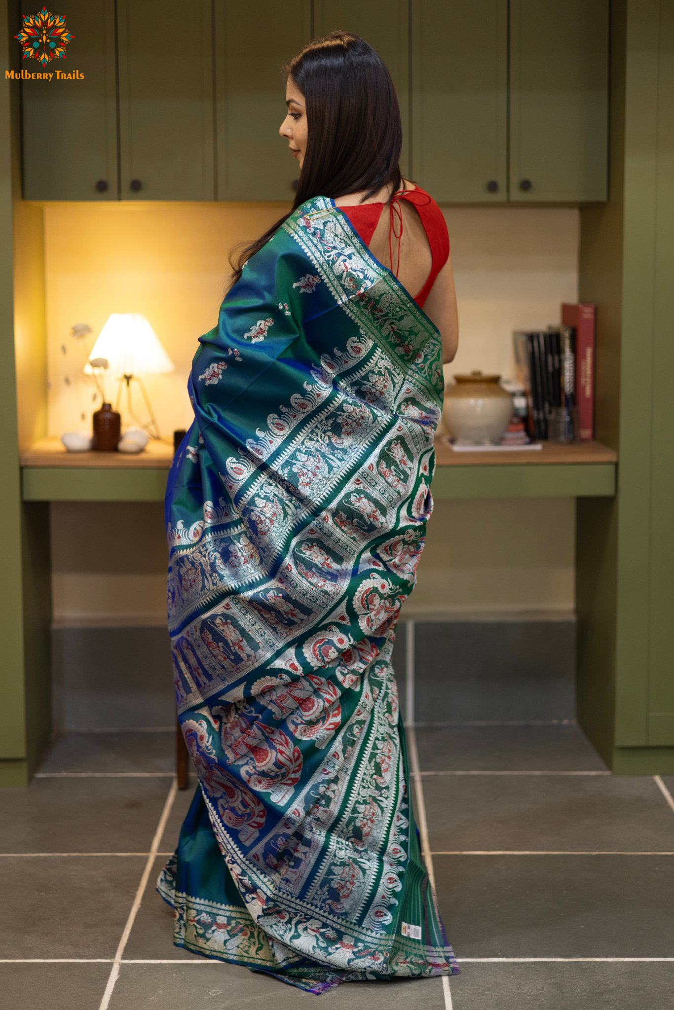 Woman in a Peacock blue and silver resham work saree standing indoors with a desk and lamp in the background.
Woman wearing a Peacock blue saree with a pattern in a elegant setting. 

Baluchari – Pure Silk Meenakari Saree

1. “Pure silk Baluchari Meenakari saree with meenakari motif weave and Silver resham detailing for a regal look.”

2. “Silk Mark pure silk meenakari saree featuring intricate gold resham work motifs and rich texture.” 