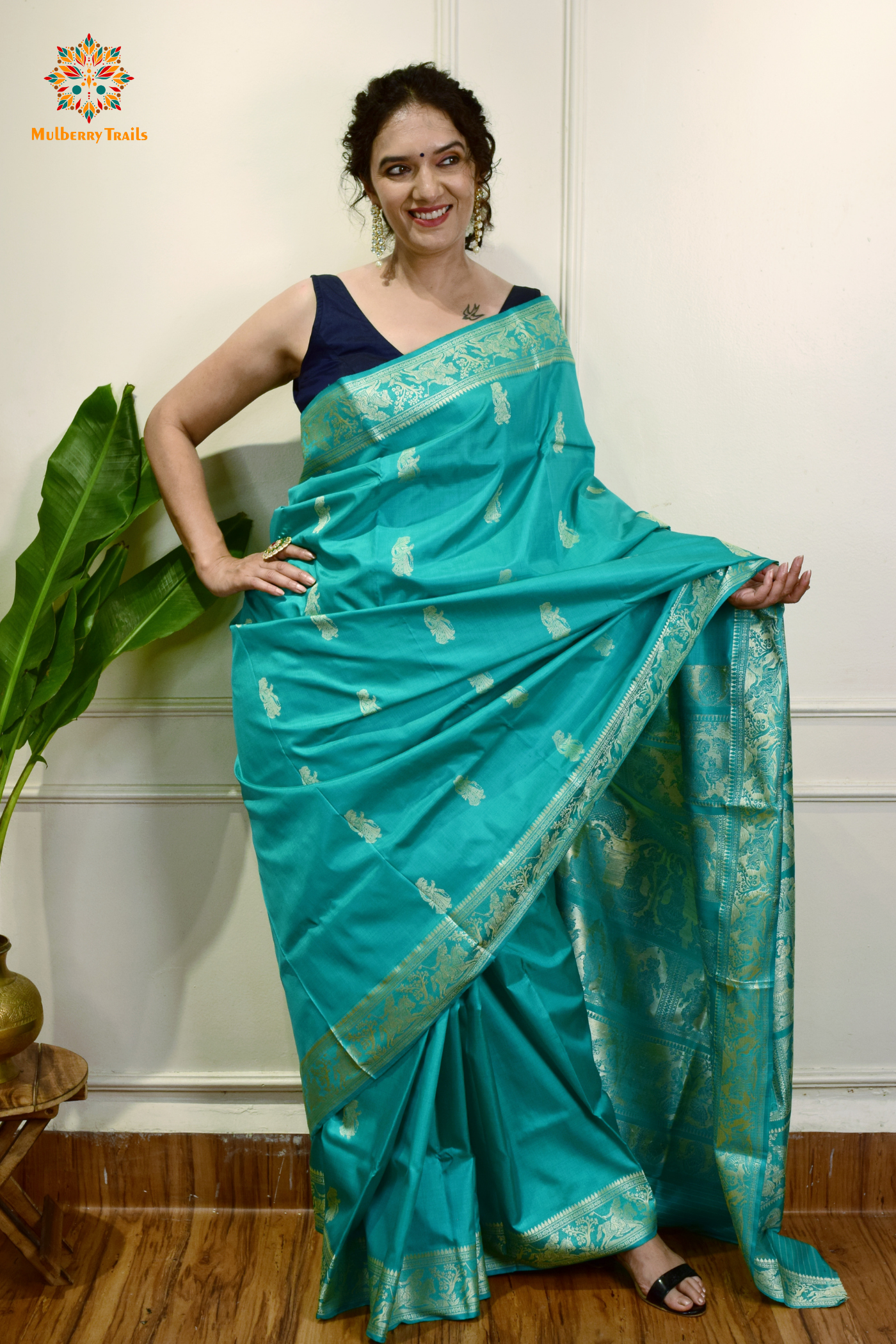 A woman wearing a Aqua Blue Baluchari Pure SIlk saree. purple baluchari silk , bengal silk saree with deer motif on pallu and ramayan, mahabharat motifs on pallu. This is a soft pure silk saree suitable for weddings, parties, festivities. suitable for Durga Puja shopping enthusiasts and diwali festival. 