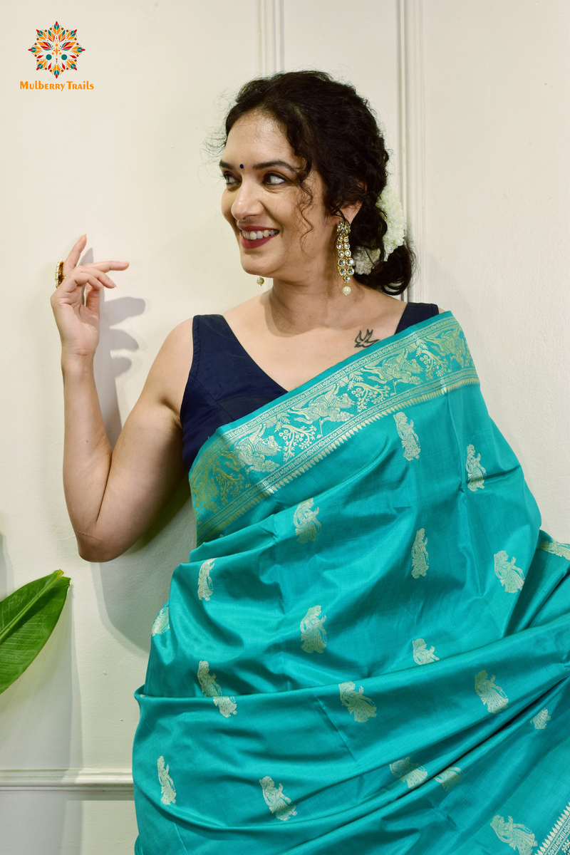 A woman wearing a Purple Baluchari Pure SIlk saree. purple baluchari silk , bengal silk saree with deer motif on pallu and ramayan, mahabharat motifs on pallu. This is a soft pure silk saree suitable for weddings, parties, festivities. suitable for Durga Puja shopping enthusiasts and diwali festival. 