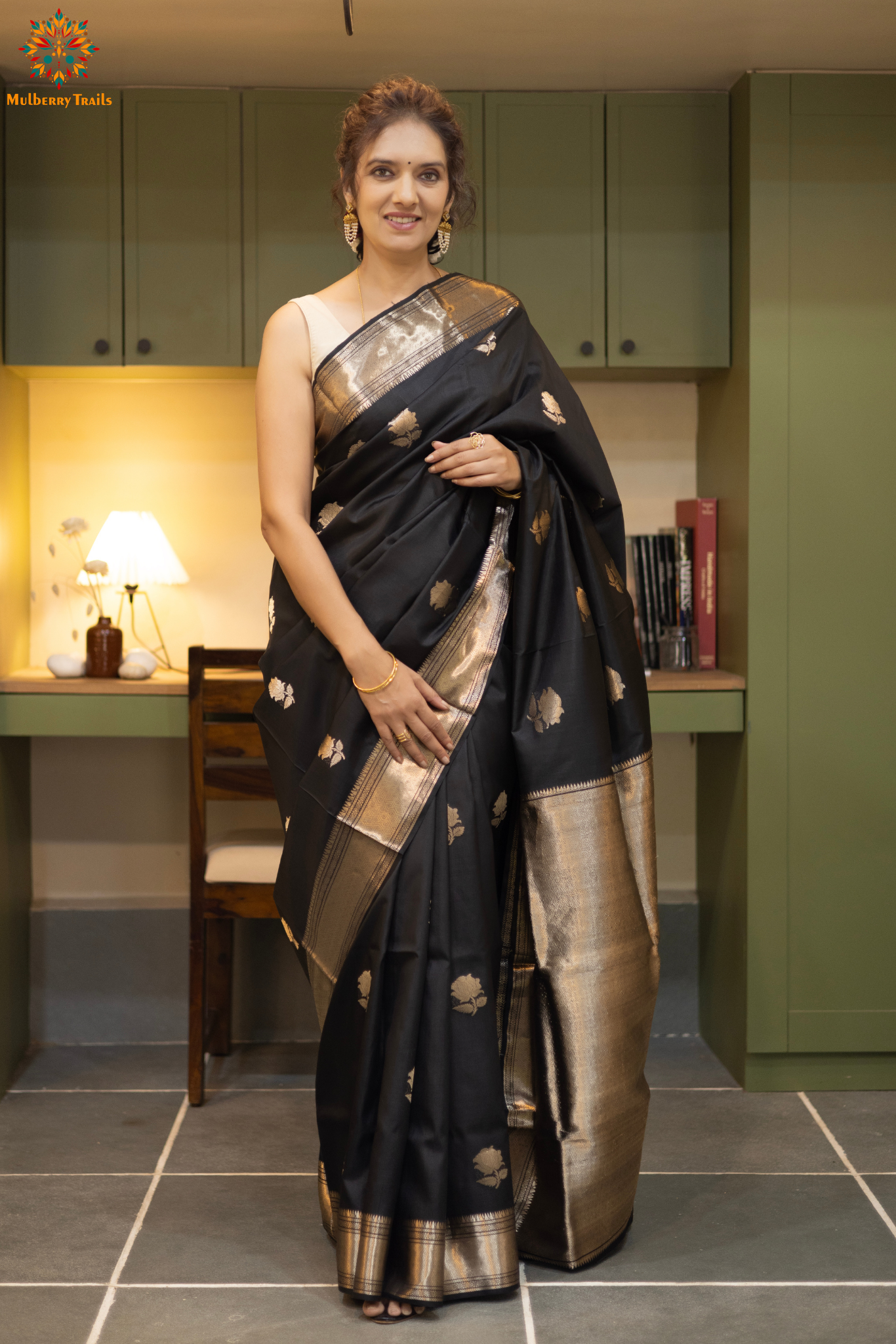 Woman in a black saree with gold patterns sitting indoor. Woman wearing a traditional baluchari saree in a room with a desk and lamp. Woman in a carrot red and silver resham work saree standing indoors with a desk and lamp in the background.

Baluchari – Pure Silk Baluchari Saree

1. “Pure silk Baluchari saree with temple motif weave and Silver resham detailing for a regal look.”

2. “Silk Mark pure silk saree featuring intricate gold resham work motifs and rich texture. 