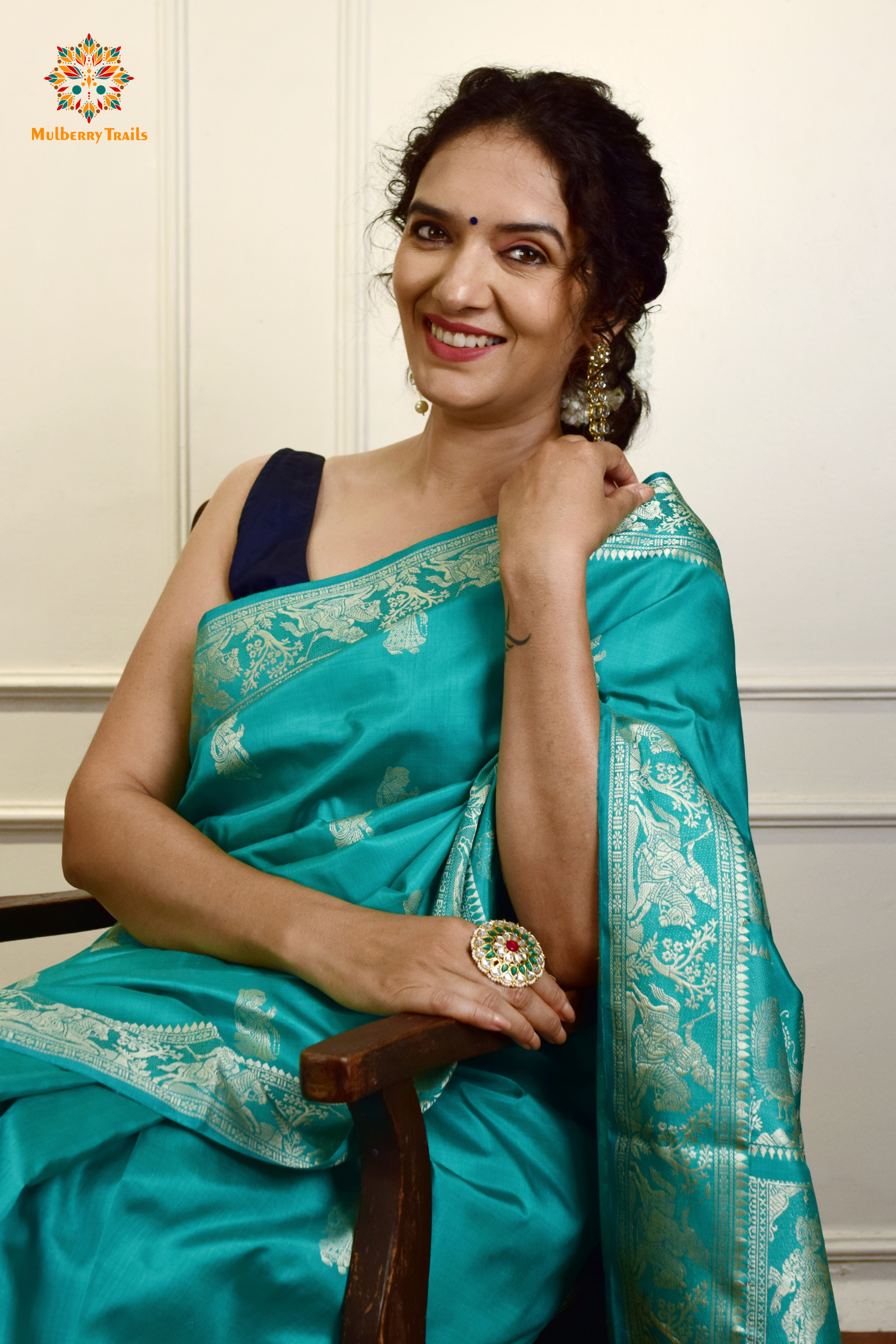 A woman wearing a Aqua Blue Baluchari Pure SIlk saree. purple baluchari silk , bengal silk saree with deer motif on pallu and ramayan, mahabharat motifs on pallu. This is a soft pure silk saree suitable for weddings, parties, festivities. suitable for Durga Puja shopping enthusiasts and diwali festival. 